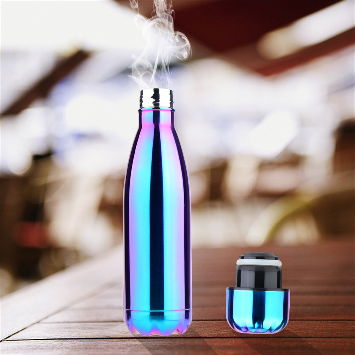 Eine glänzende, schillernde Wasserflasche mit sichtbarem Dampf, daneben der offene Deckel auf einer Holzoberfläche.