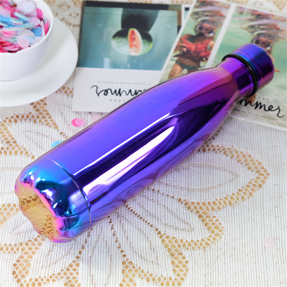 Eine metallisch-lila Wasserflasche mit Gradient-Effekt. Sie liegt auf einem Tisch.