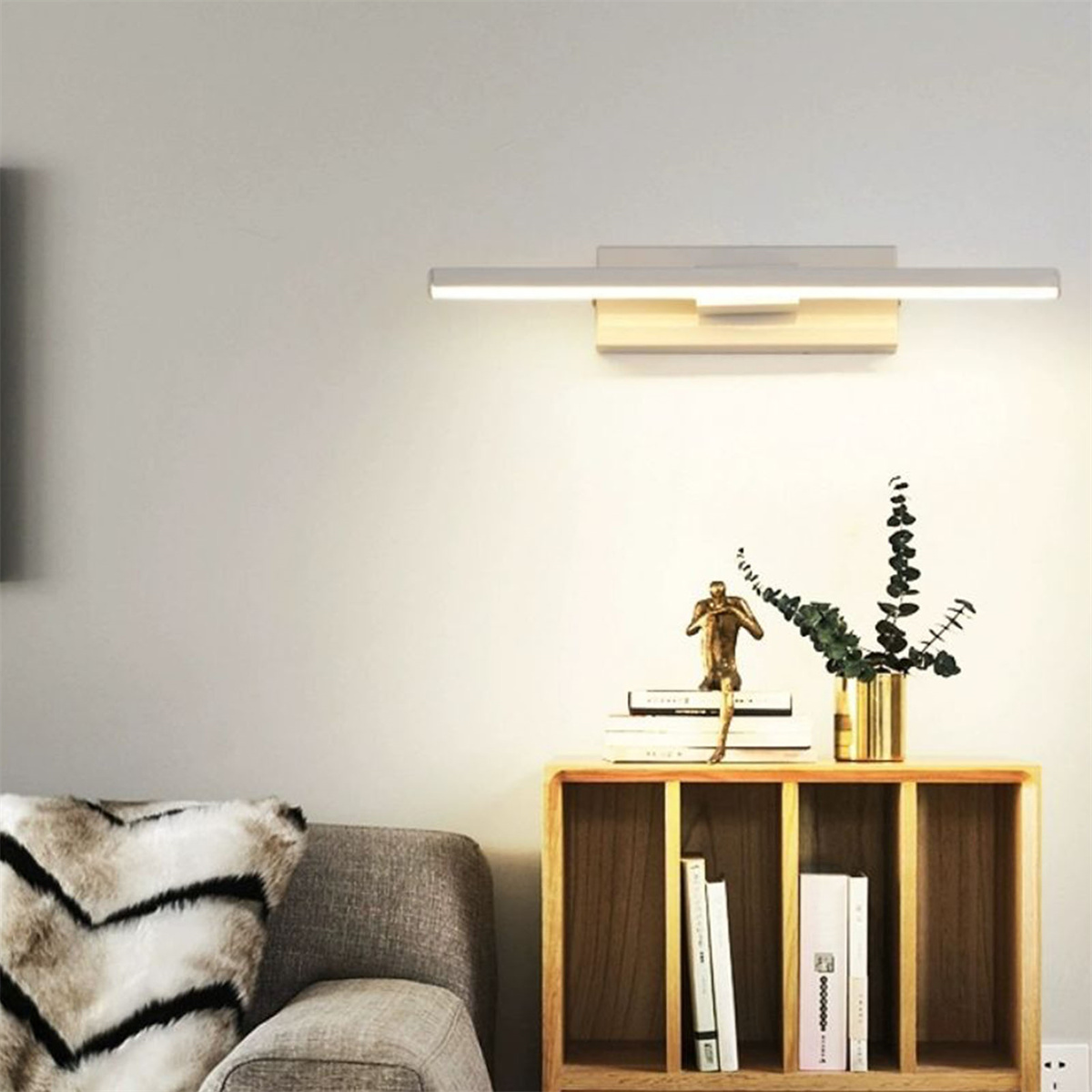 Wandlampe aus Holz mit Lichtleiste, Skulptur, Büchern und einer Pflanze in goldener Vase.