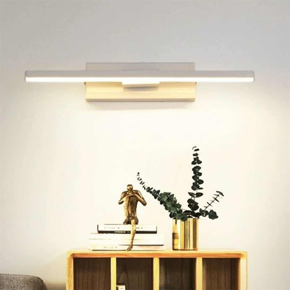 Wandleuchte mit Holzsockel, Metallskulptur und Vase mit Grün auf einem Regal.