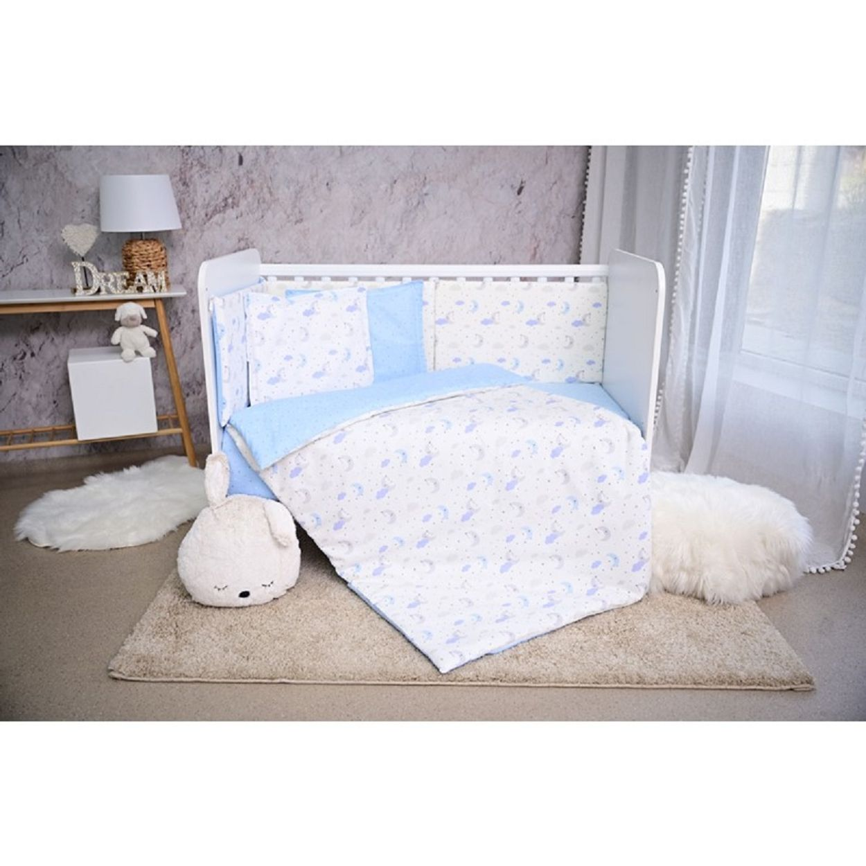 Ein Babybett-Set mit blauem und weißem Mond- und Sterndesign auf neutralem Hintergrund.