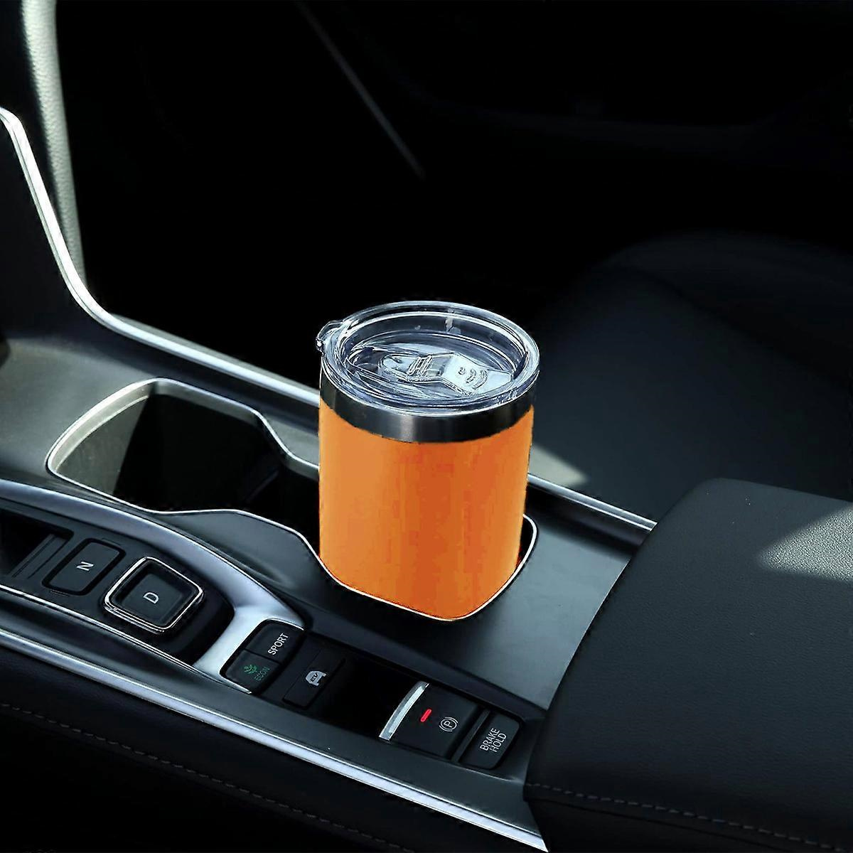 Ein orangefarbener Becher in einem Getränkehalter im Auto. Der Innenraum eines Autos ist sichtbar. Der Hintergrund ist dunkel.