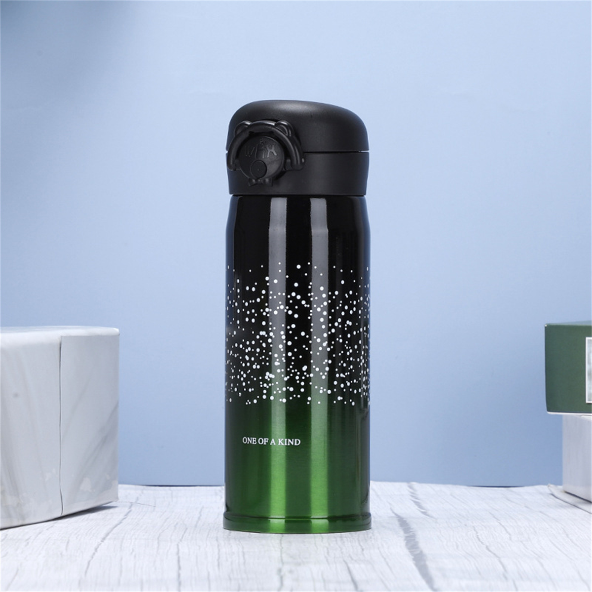 Eine grüne und schwarze Wasserflasche mit schwarzem Deckel und dem Text 'ONE OF A KIND' auf blauem Hintergrund.
