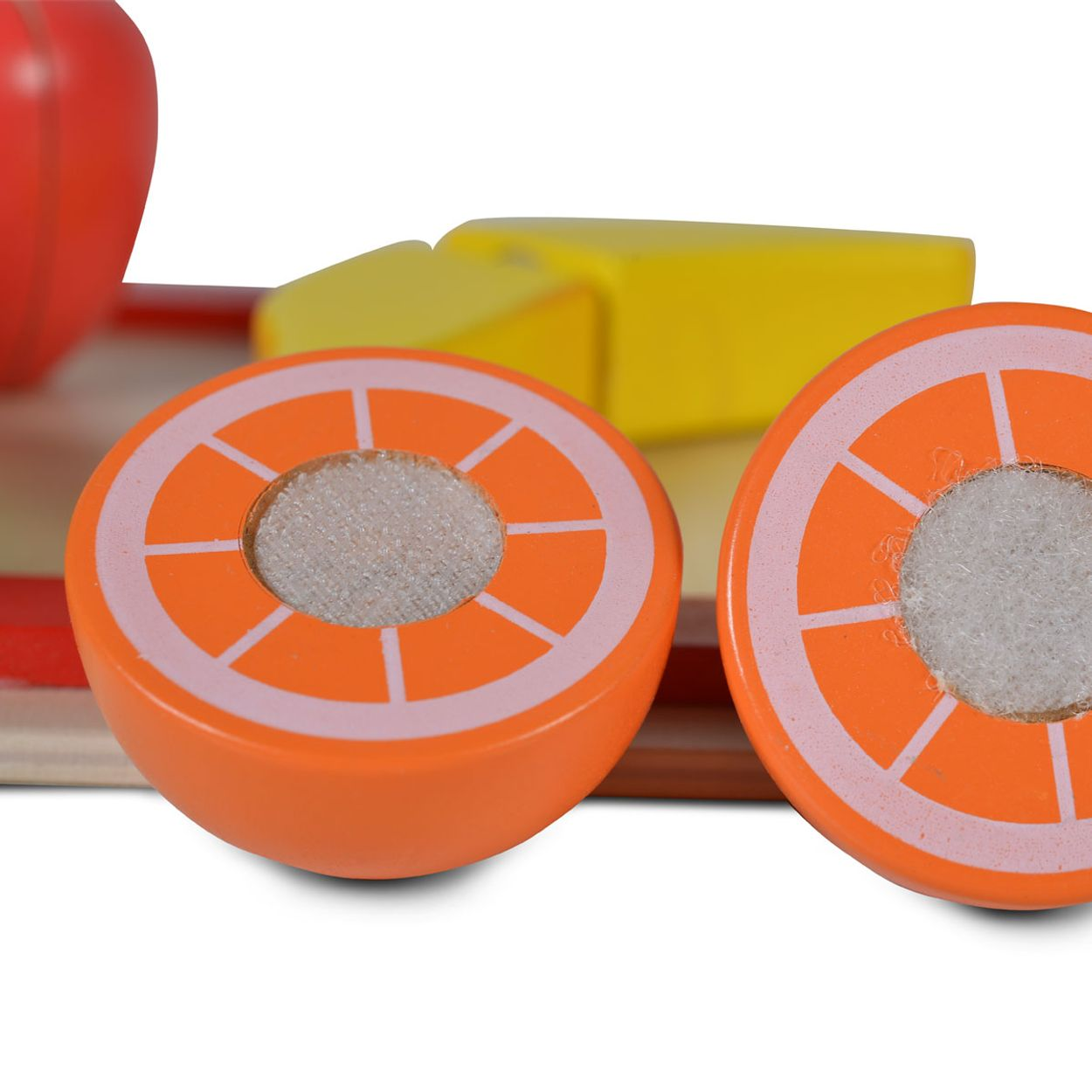 Holzspielzeug-Fruchtscheiben, orange mit weißem Zentrum, neben anderen Holzfrüchten.