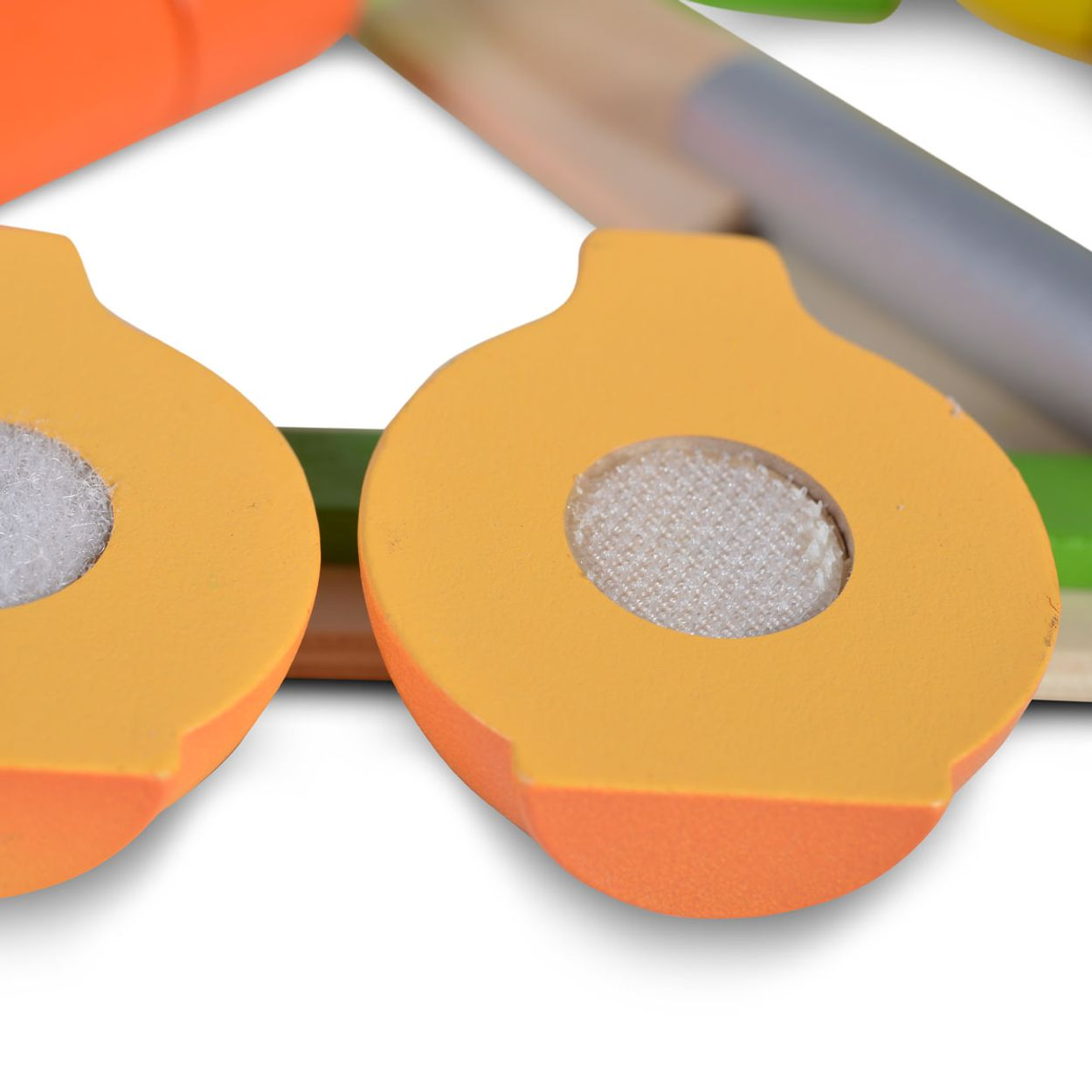 Holzspielzeug-Gemüse, halbiert. Orange und grüne Farben. Weißer Hintergrund.