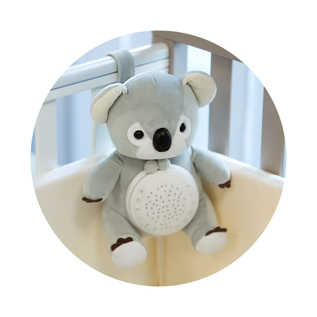 Graues Koala-Plüschtier mit Sternenprojektor im Bauch, hängt im Kinderbett.