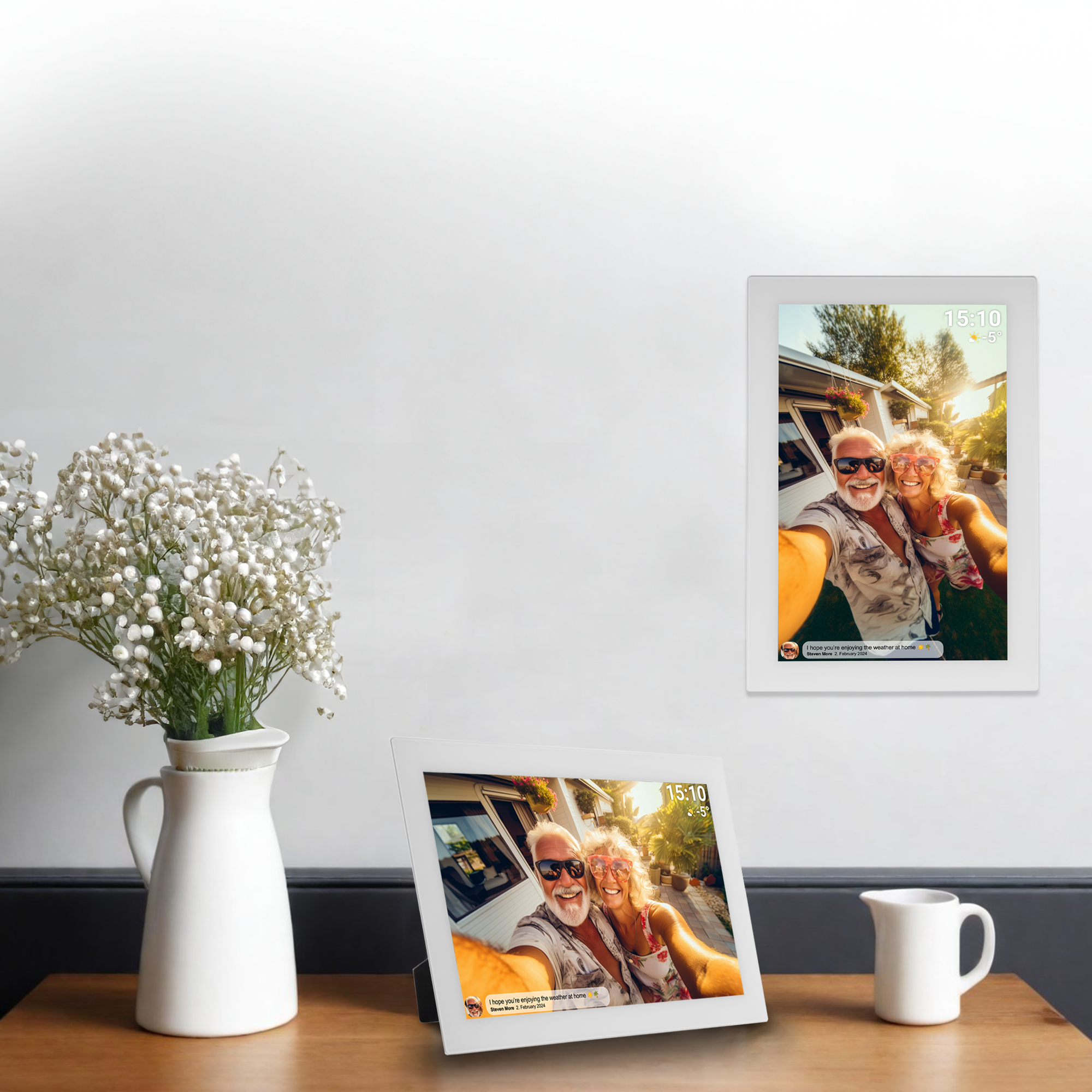 Un cadre photo numérique blanc sur une surface en bois. Un vase avec des fleurs est à gauche.