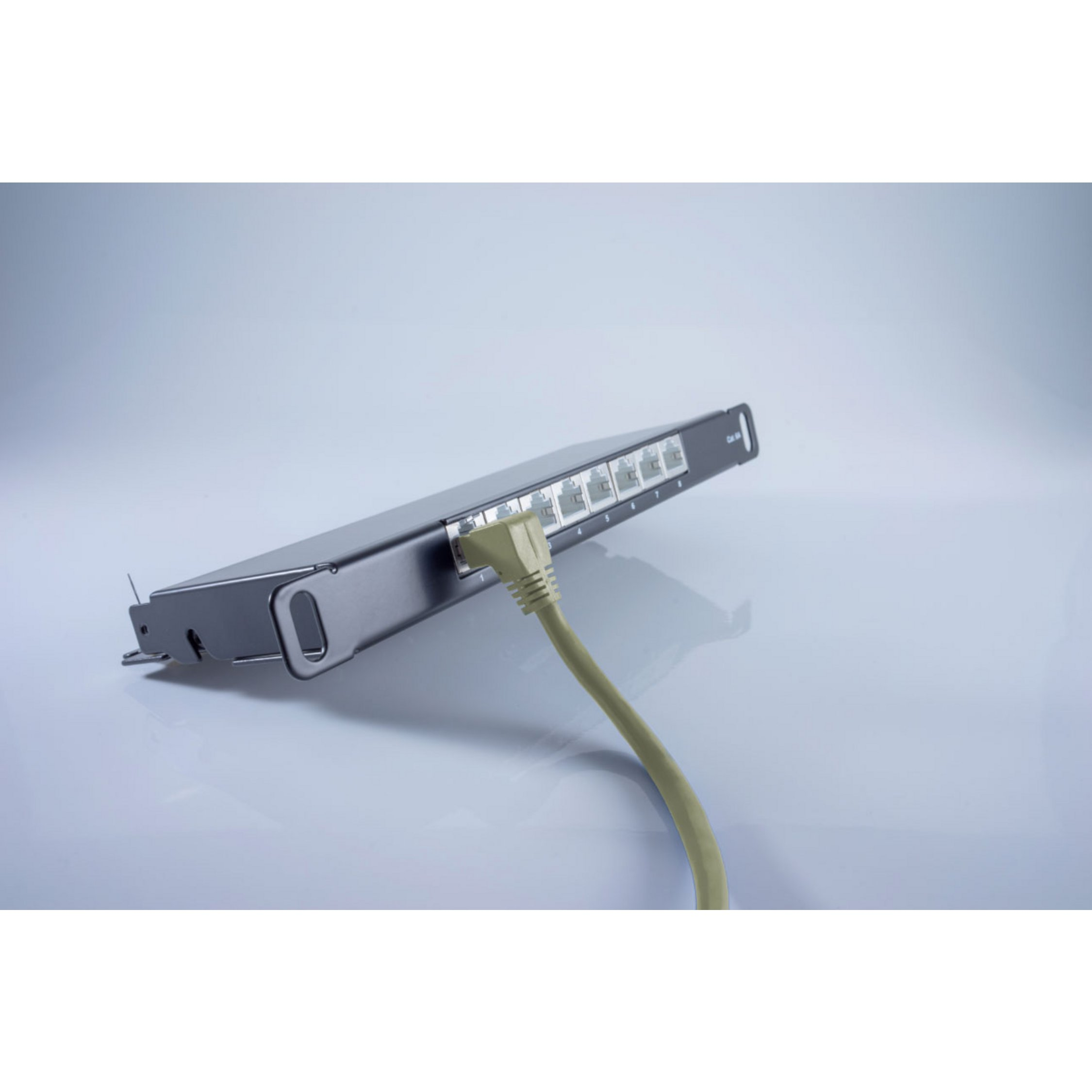 Czarny przełącznik sieciowy z wpiętym żółtym kablem. Przełącznik leży na białej powierzchni.