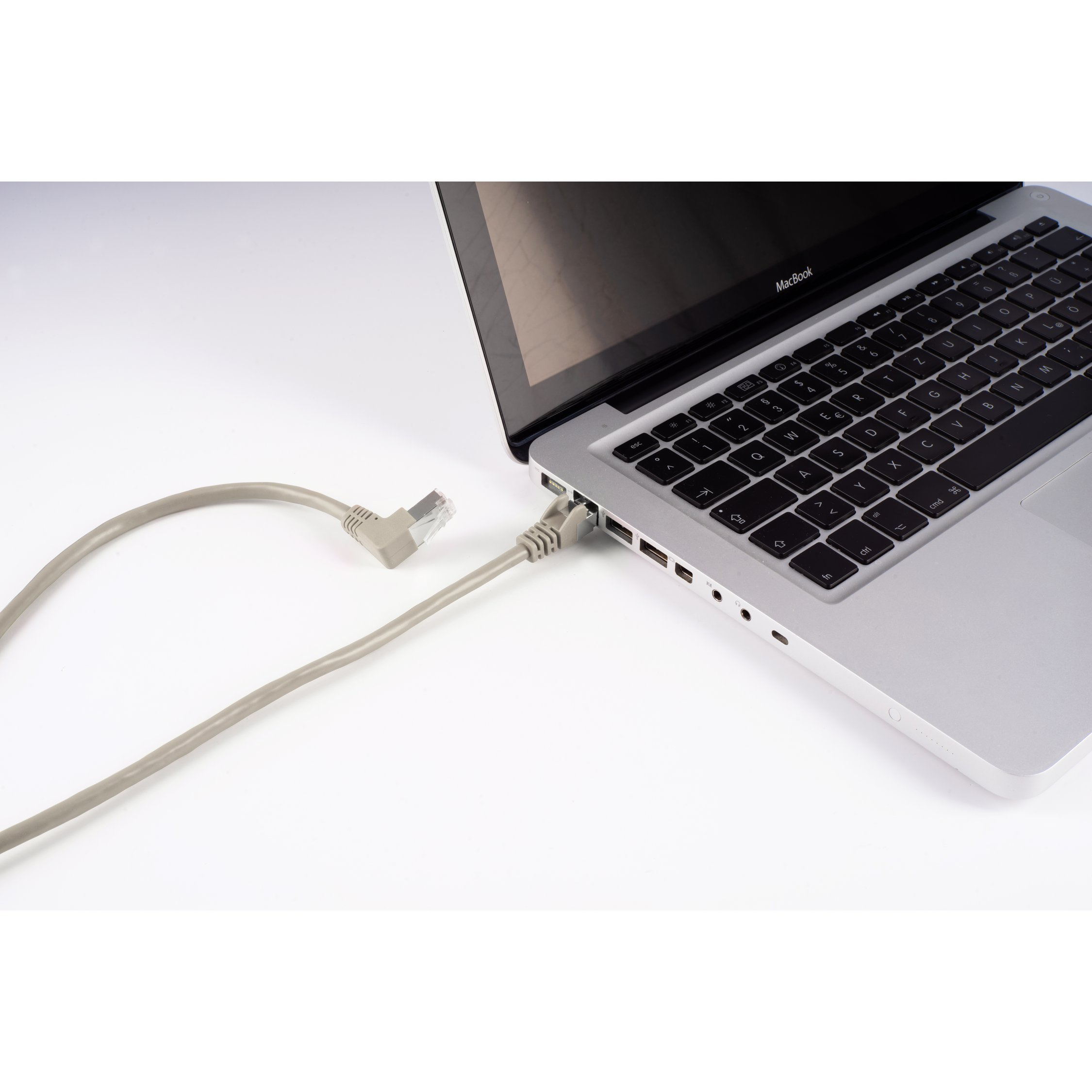 Laptop podłączony do kabla ethernet na białej powierzchni.