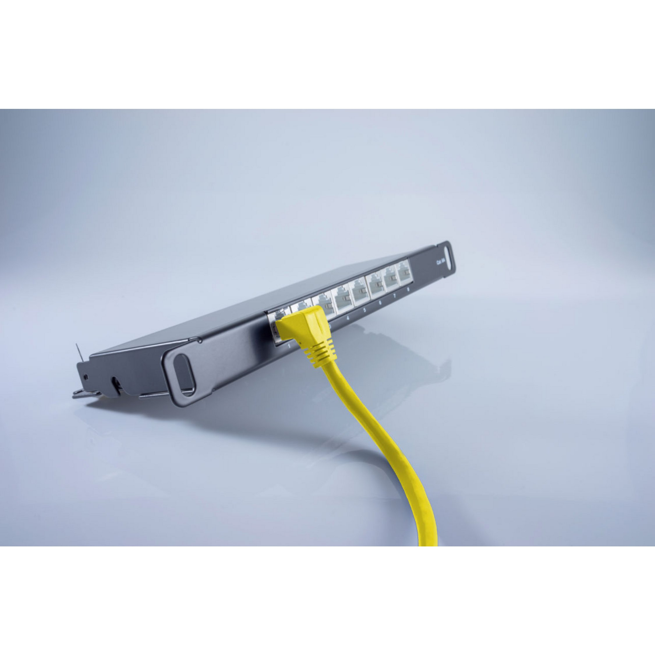 Uno switch di rete nero con un cavo Ethernet giallo collegato, su una superficie grigio chiaro.