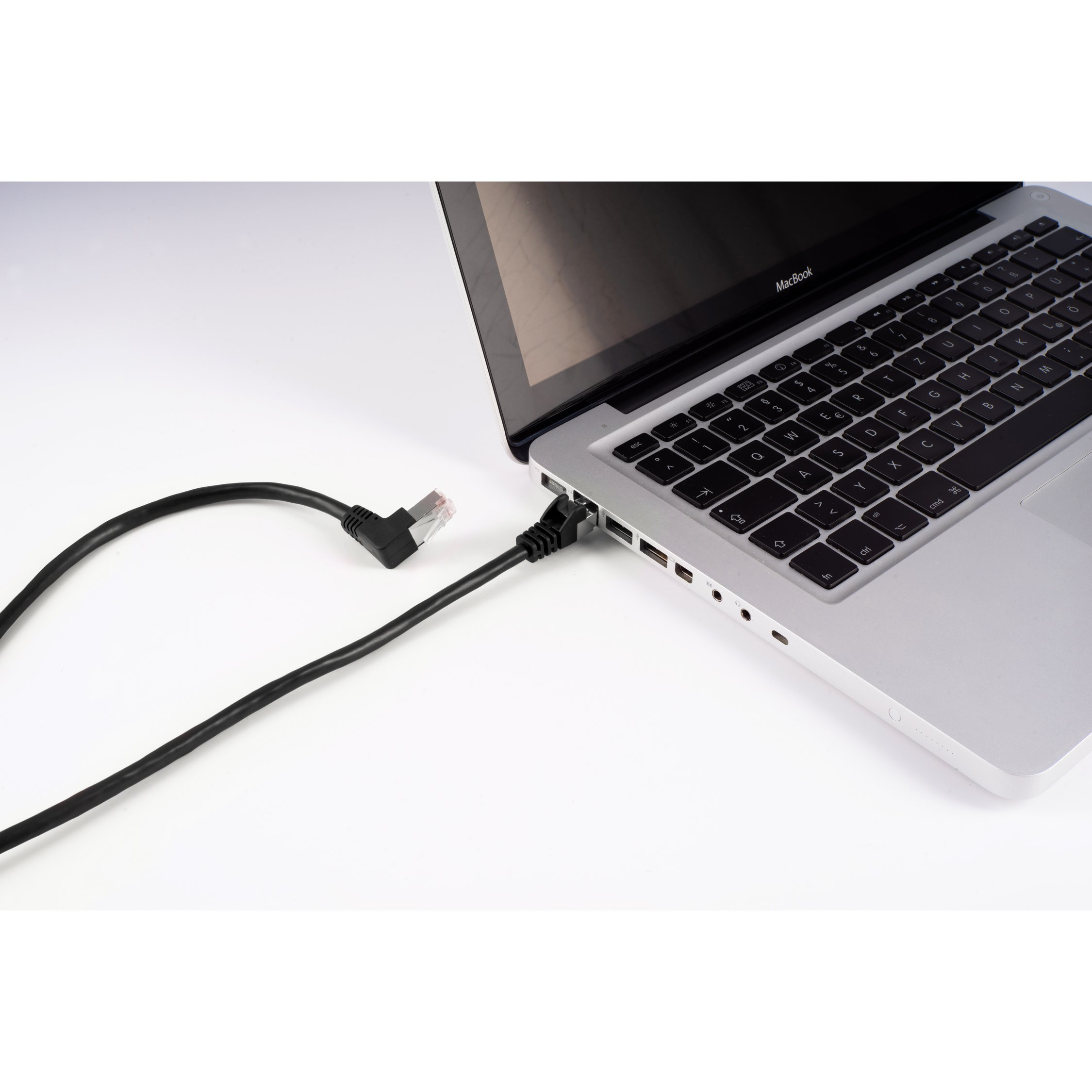 Laptop collegato a un cavo Ethernet nero su una superficie bianca. Cavo collegato.