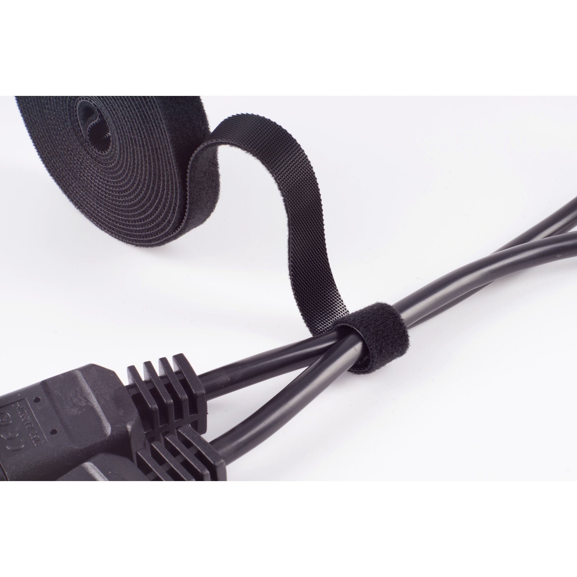 Schwarze Klett-Kabelbinder wickeln sich um zwei schwarze Kabel vor weißem Hintergrund.