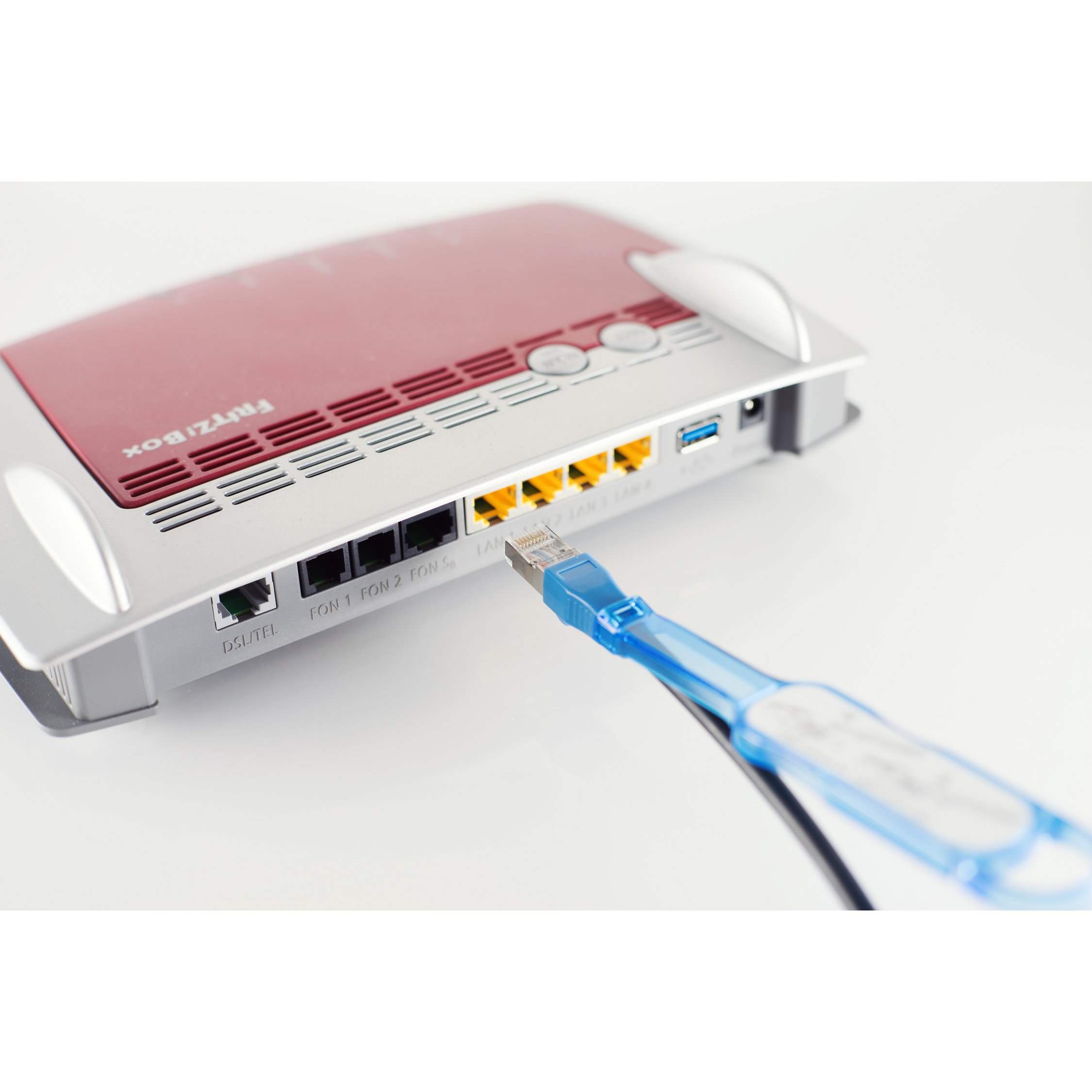 Router rosso e argento con cavo blu collegato alla porta LAN, sfondo bianco.