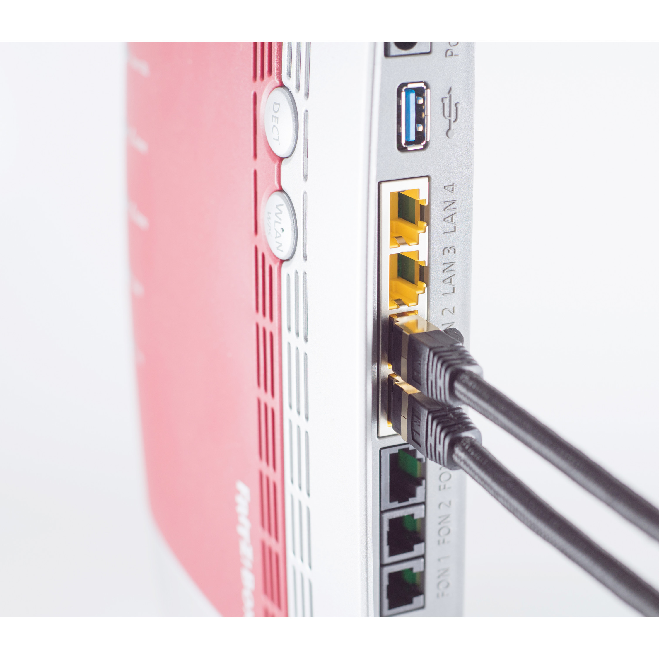 Nahaufnahme eines rot-weißen Routers mit Ethernet-Kabeln, die in die Rückseite eingesteckt sind, auf weißem Untergrund.