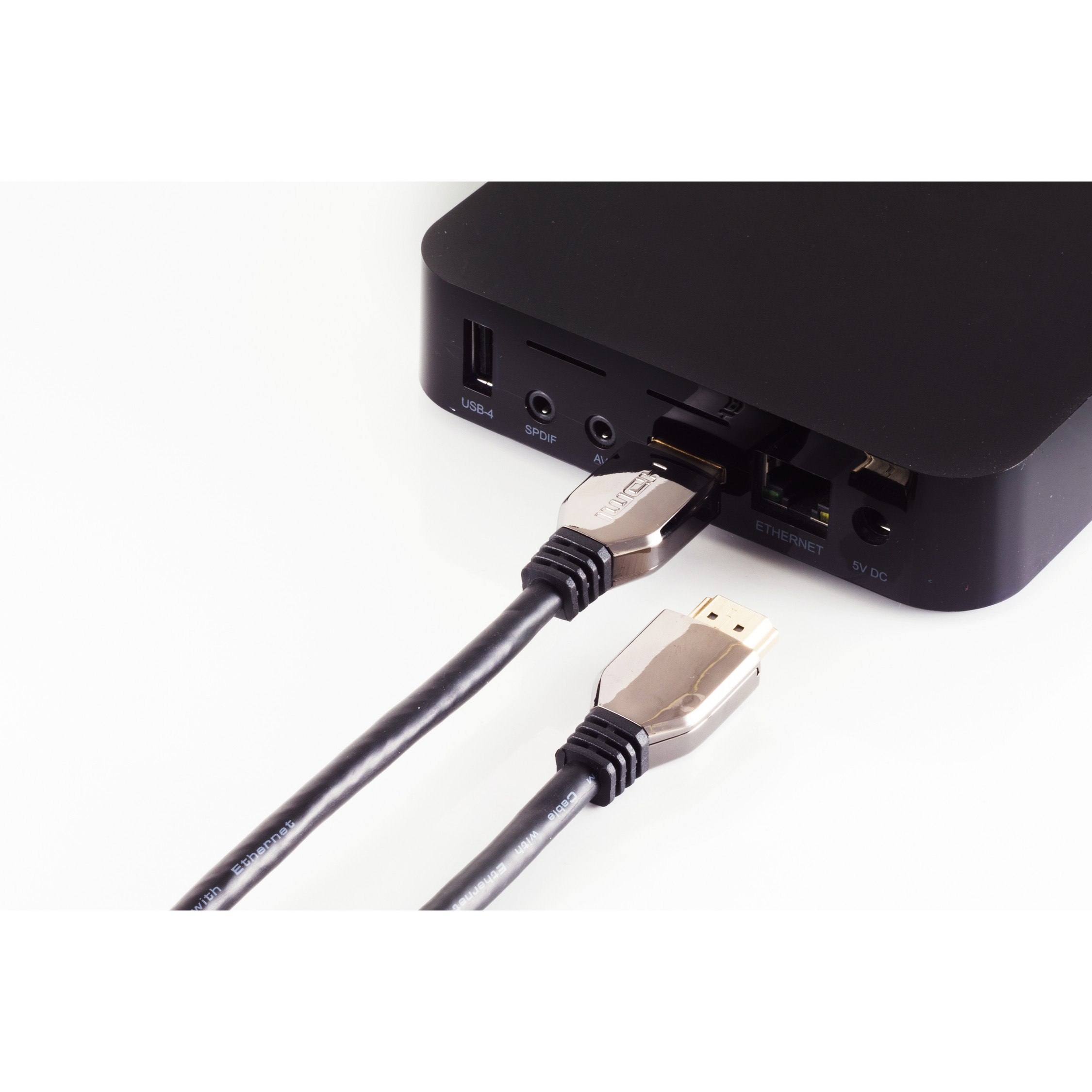 Schwarzes Gerät mit angeschlossenem HDMI-Kabel, neben einem weiteren HDMI-Kabel, alles auf weißem Hintergrund.