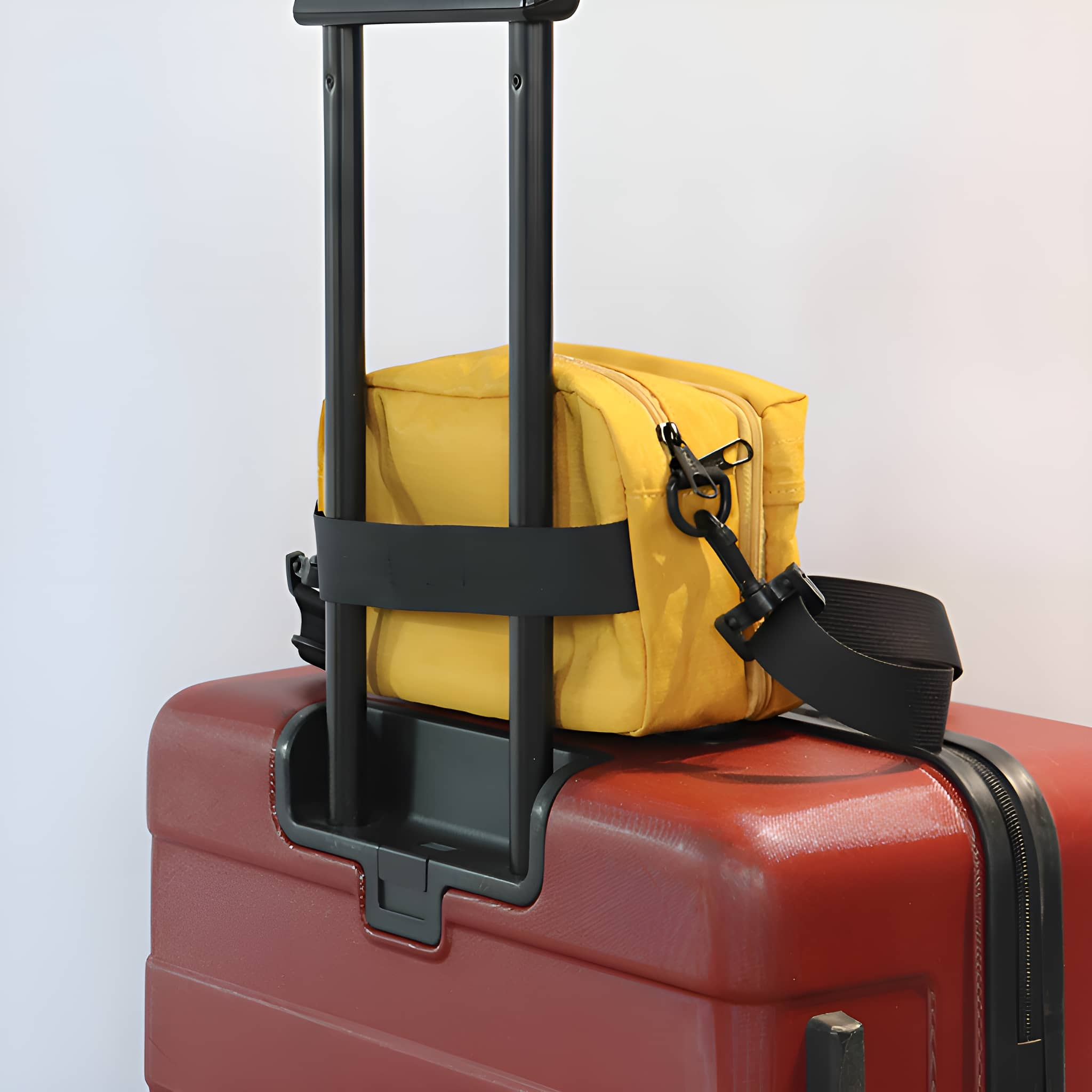 Eine gelbe Reisetasche, die mit einem schwarzen Riemen an einem roten Koffergriff befestigt ist.