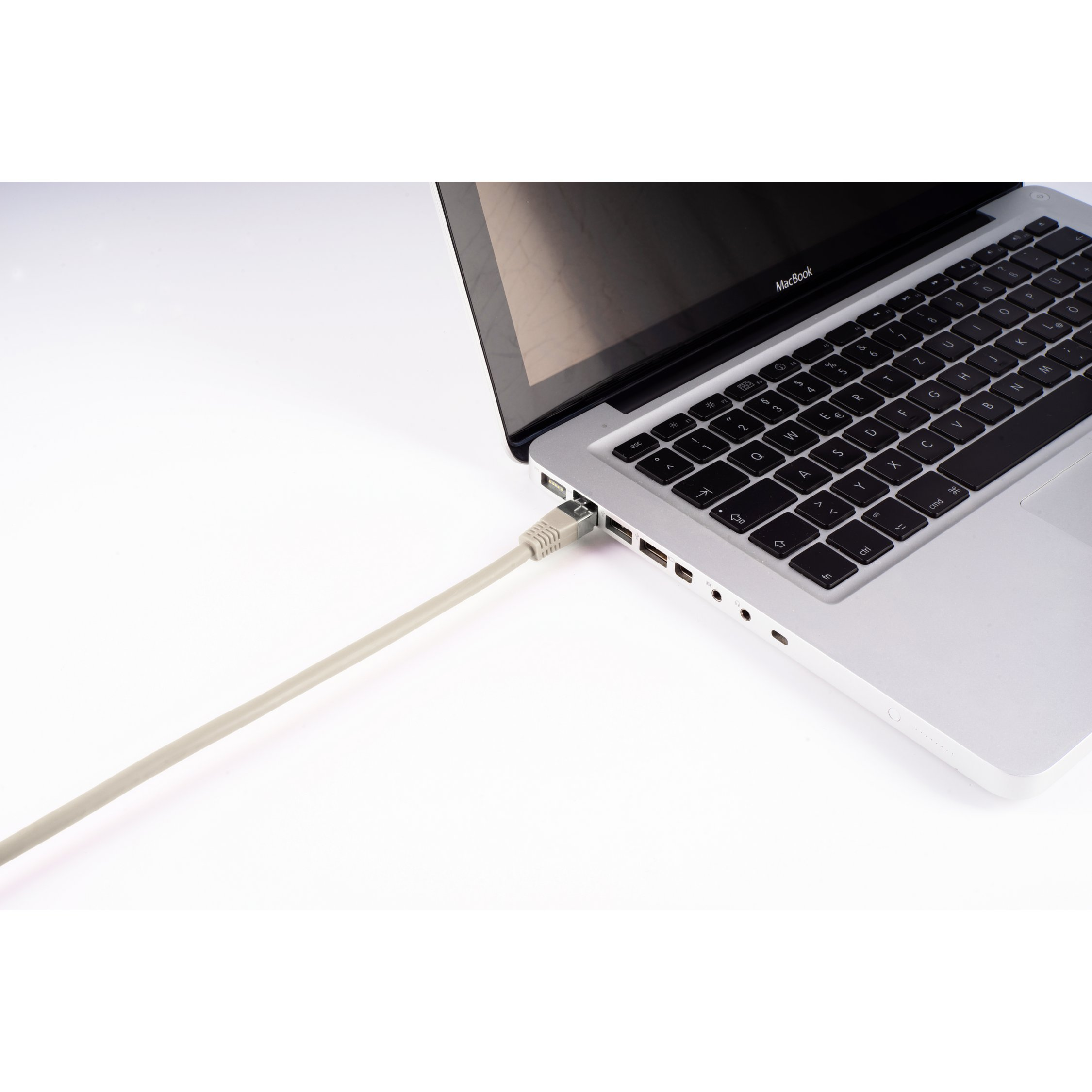 Laptop con cavo grigio chiaro collegato, su una superficie bianca. Parte del laptop visibile.
