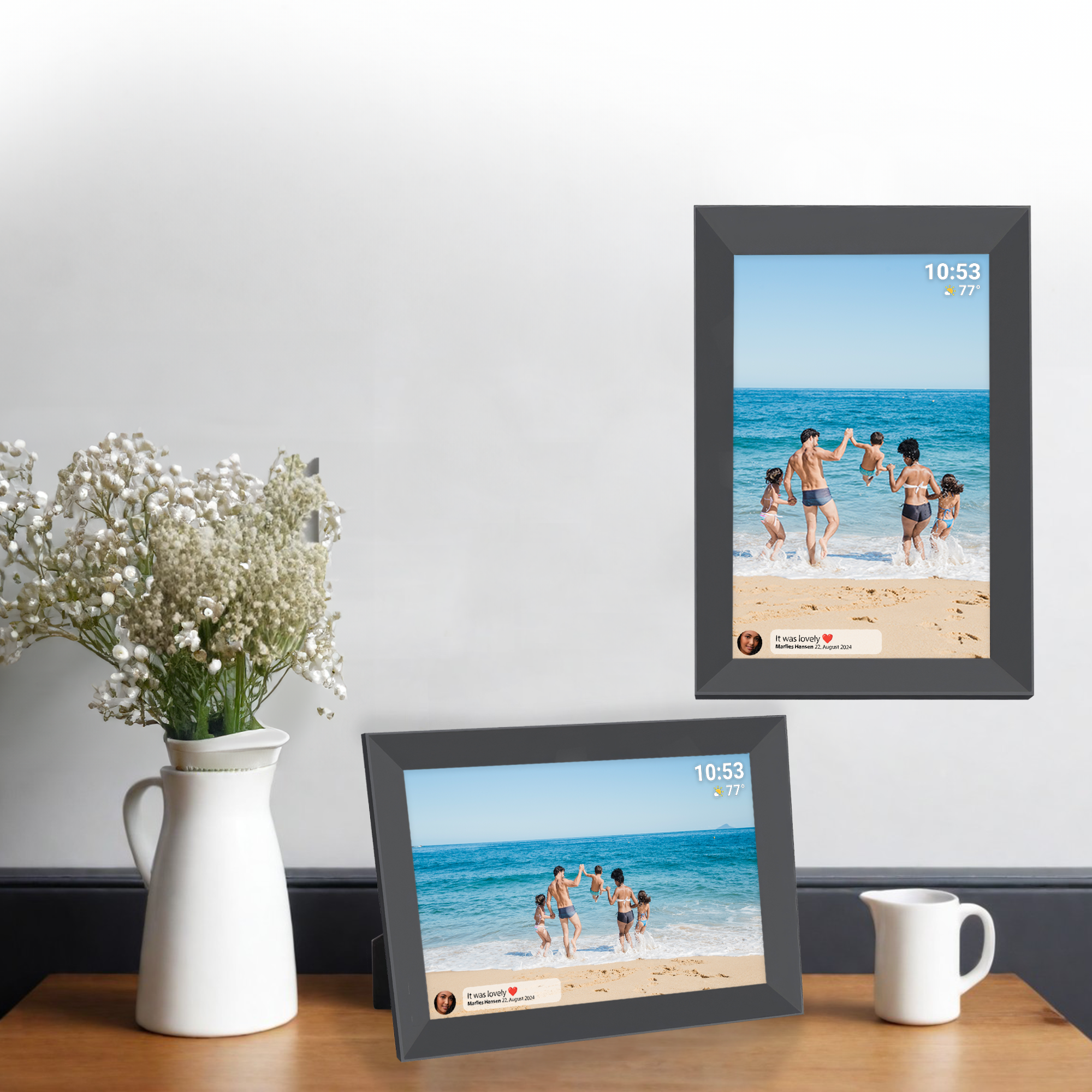 Deux cadres photo numériques affichant une scène de plage familiale, sur une table en bois.