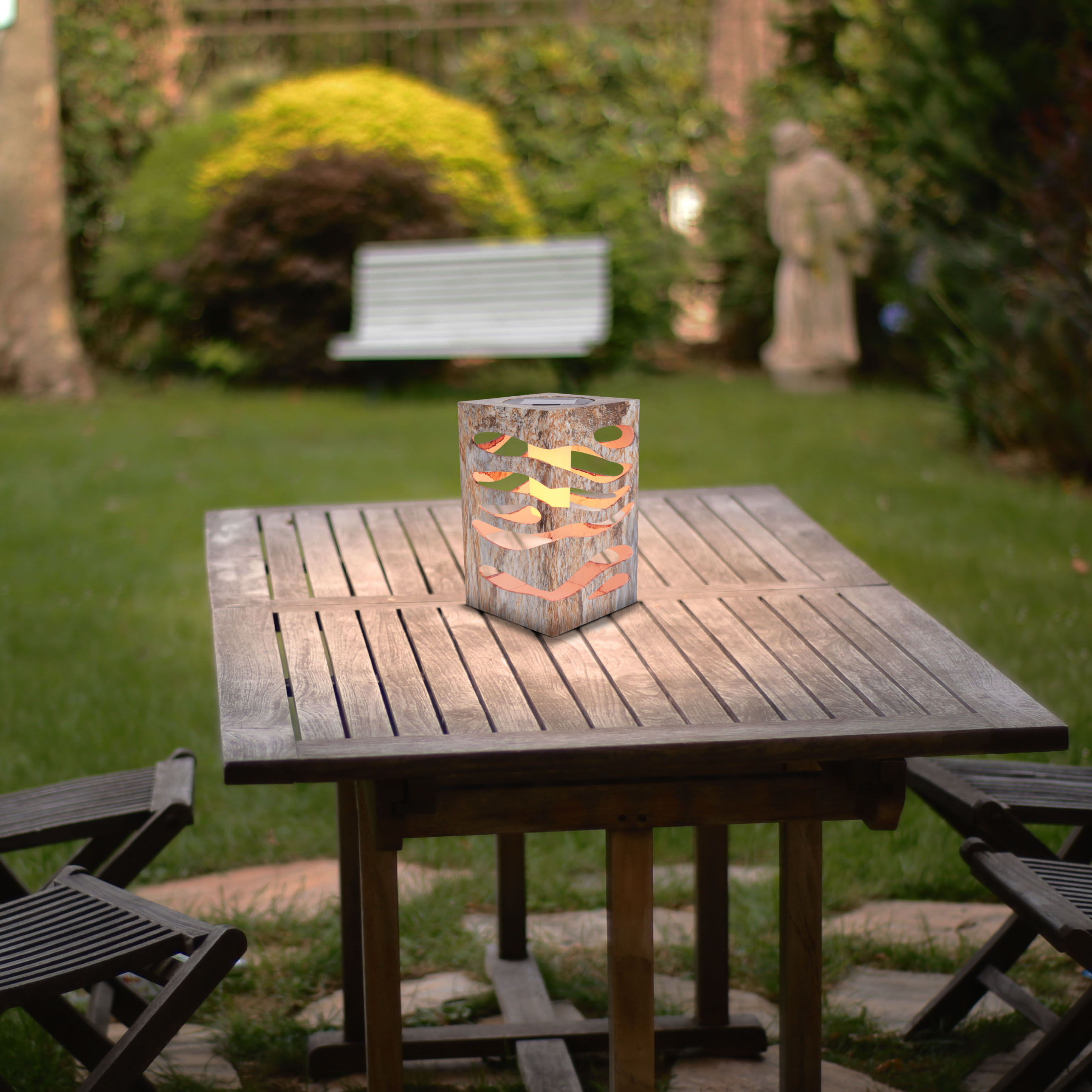 Ein Holztisch mit einer Laterne in einer Gartenszene, mit Bäumen und Gras.