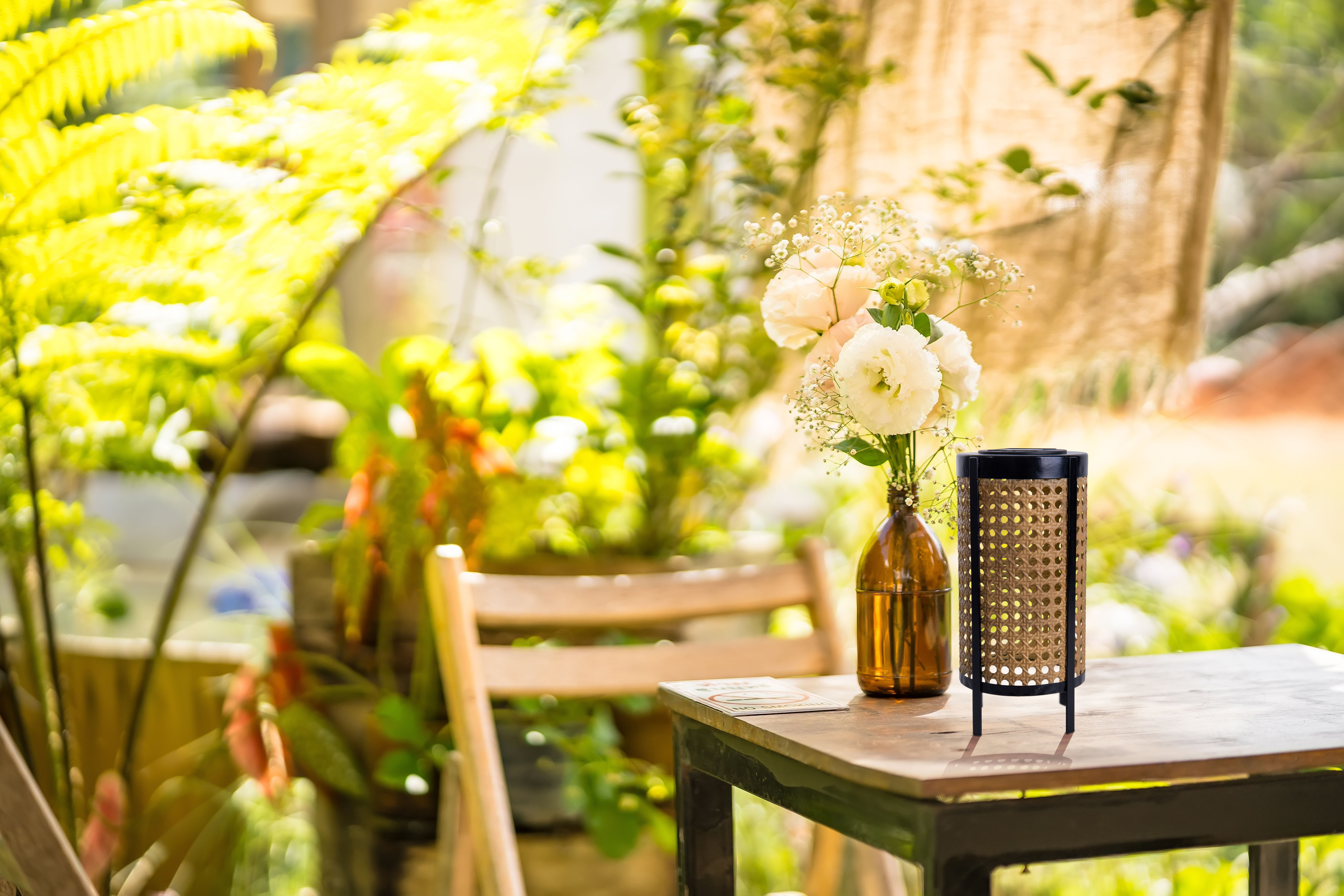 Ein Tisch auf einer Terrasse mit Blumen in einer Vase und einer dekorativen Lampe.