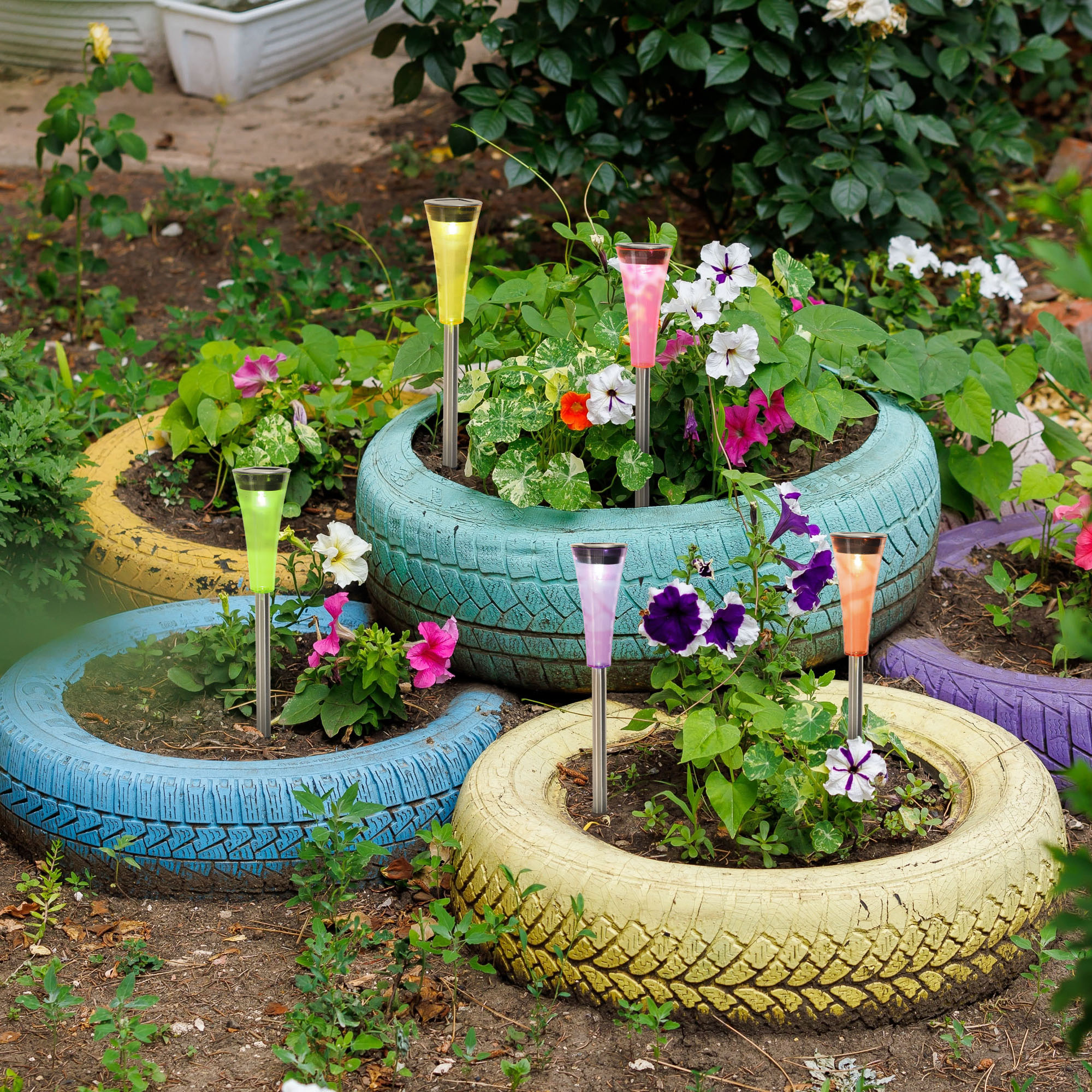 Garten mit Solarleuchten in bunten Reifen. Blumen und grüne Pflanzen.