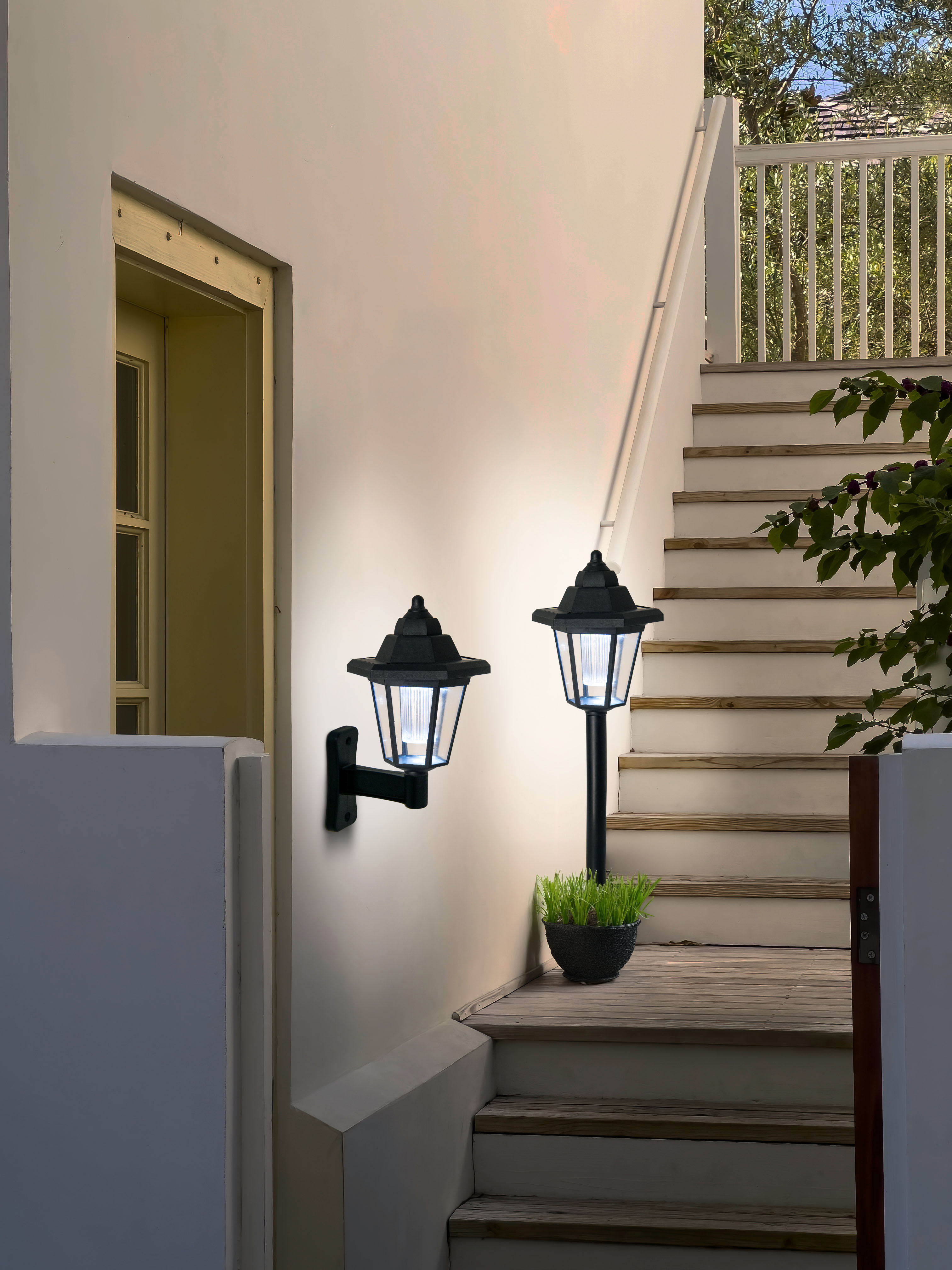 Zwei schwarze Außenlampen an einer Wand und Treppe. Hintergrund: weiße Wand und Holztreppe.