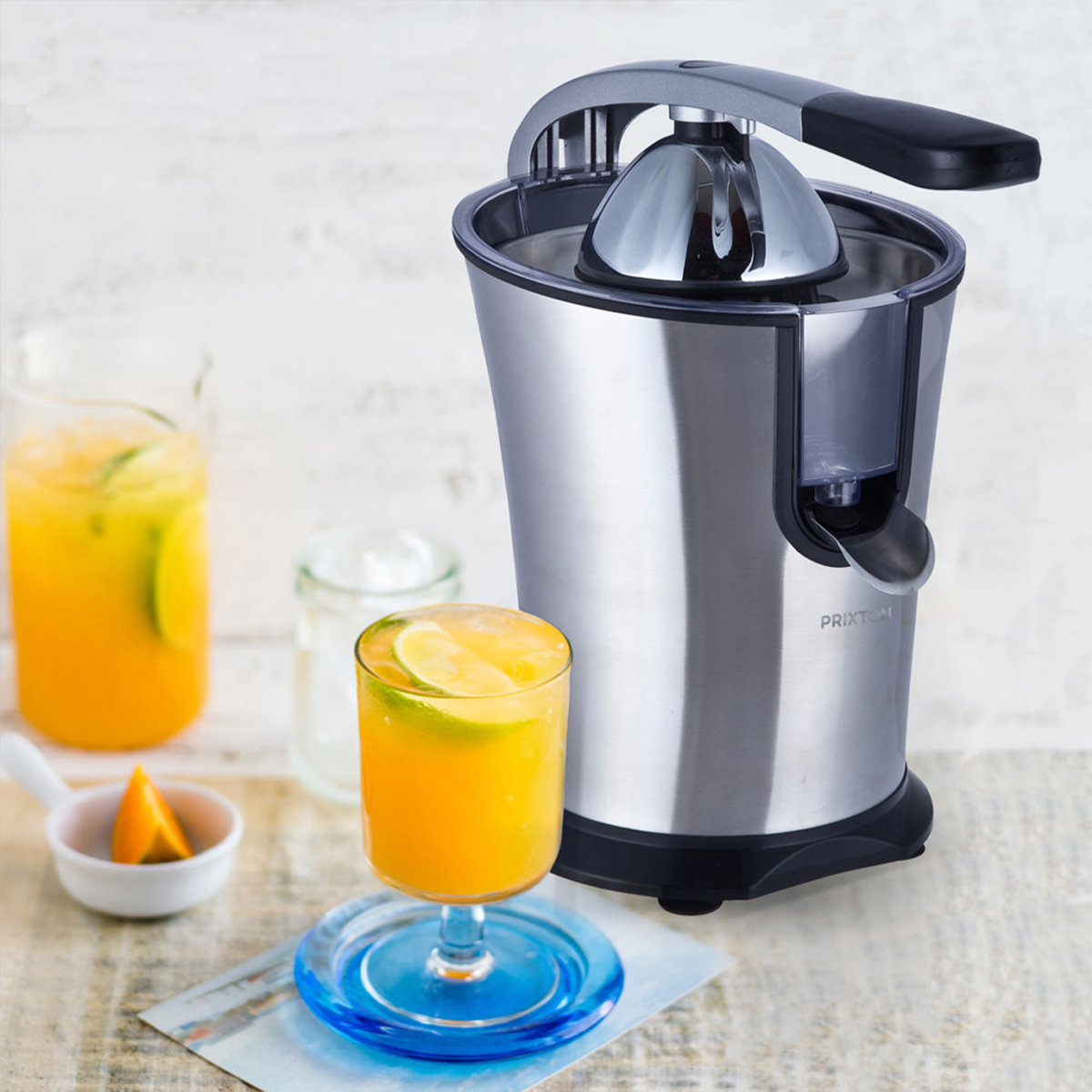 Wyiskarka ze stali nierdzewnej, szklanka z sokiem i plasterkiem limonki, sok i szklanka w tle.