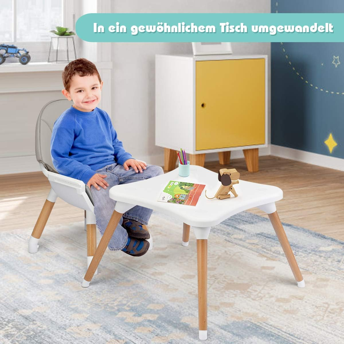 Ein Kind sitzt an einem kleinen Tisch. Ein Hochstuhl befindet sich neben dem Tisch. Ein Schrank ist im Hintergrund.