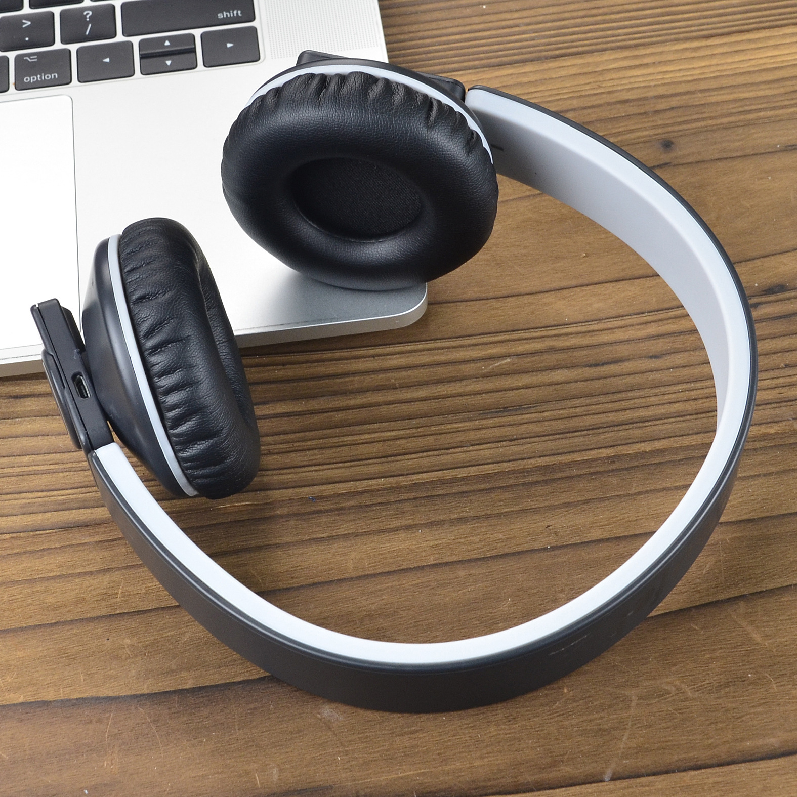 Widok z góry na czarne słuchawki z szarymi i białymi akcentami, leżące na klawiaturze laptopa.