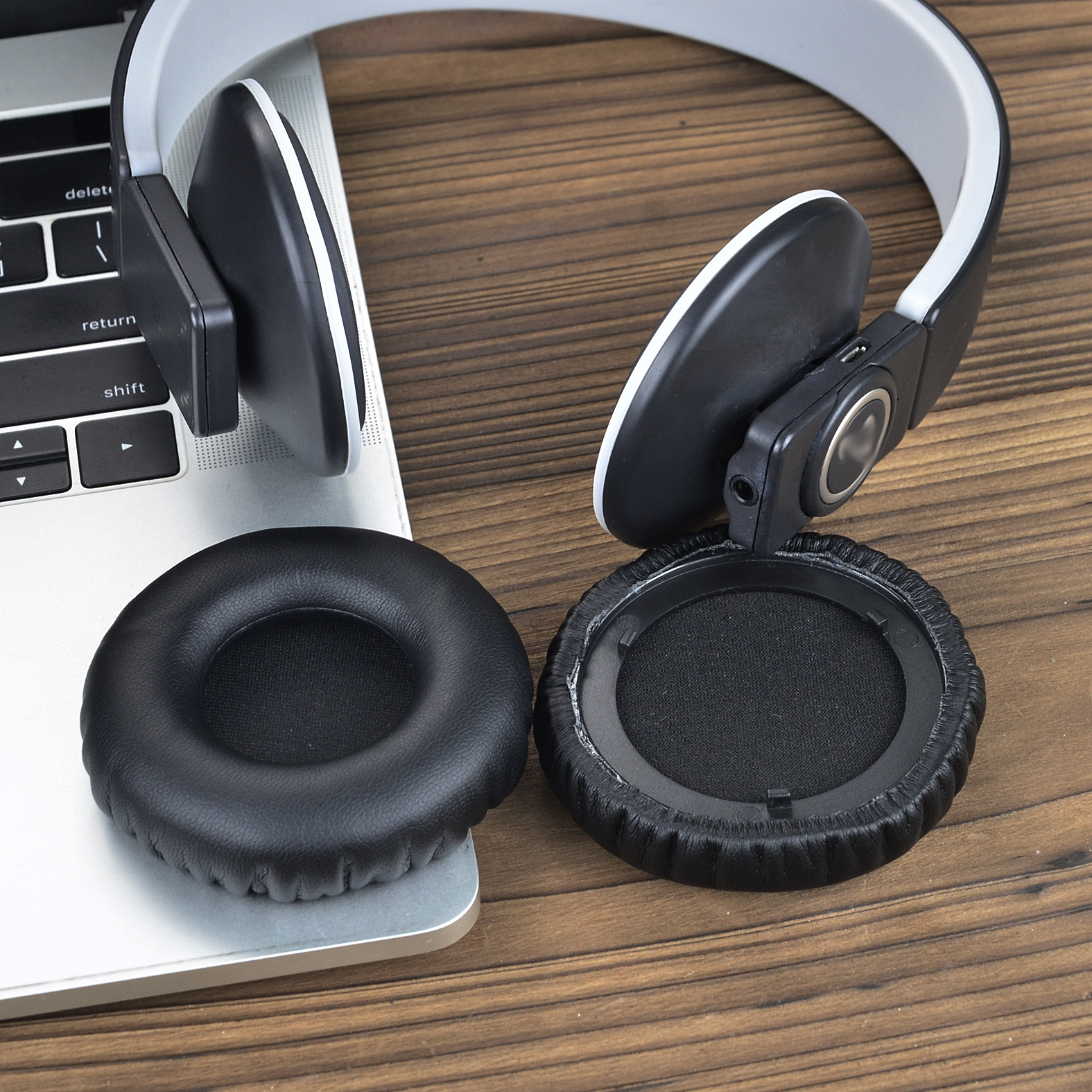 Czarne i białe słuchawki na klawiaturze laptopa. Słuchawki są otwarte.