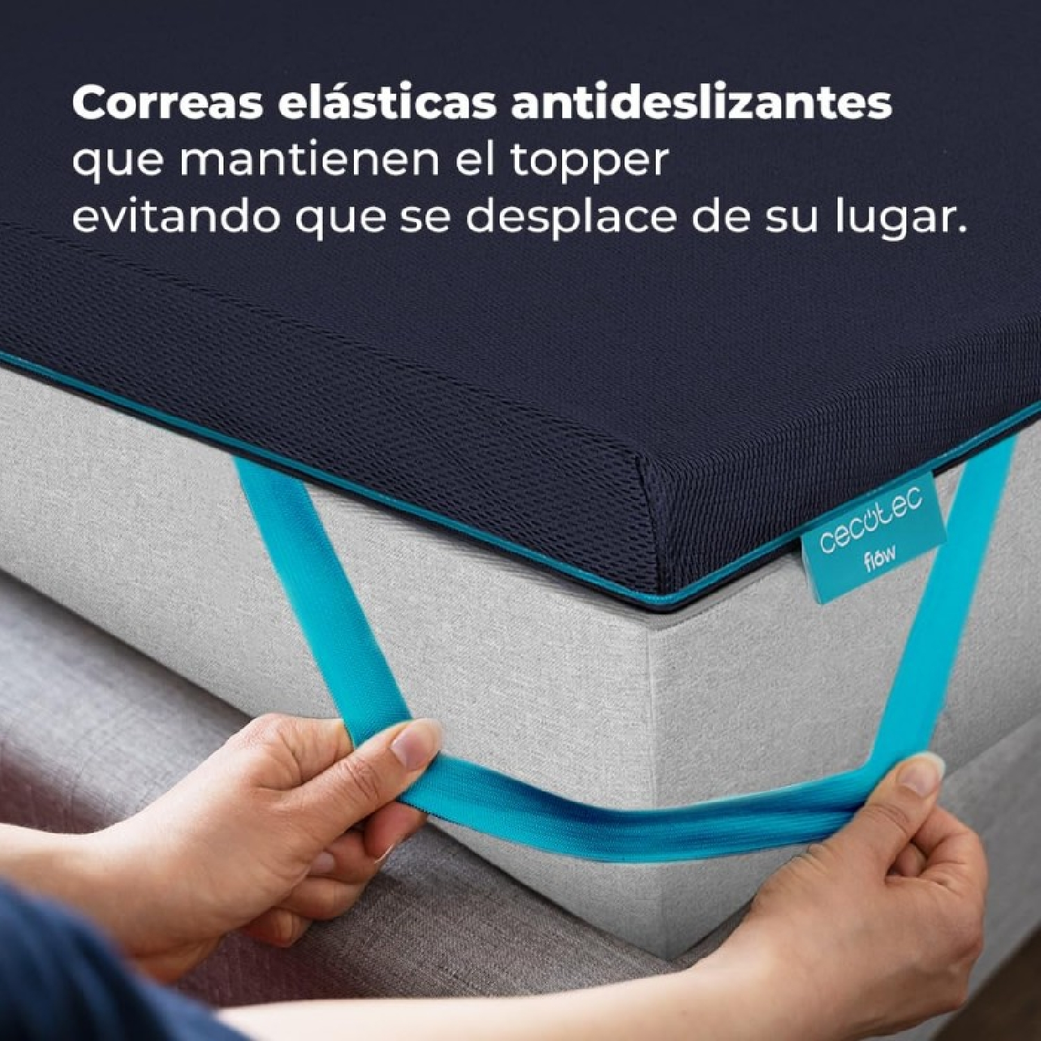 Manos sujetando correas elásticas azules en un cubrecolchón azul marino.