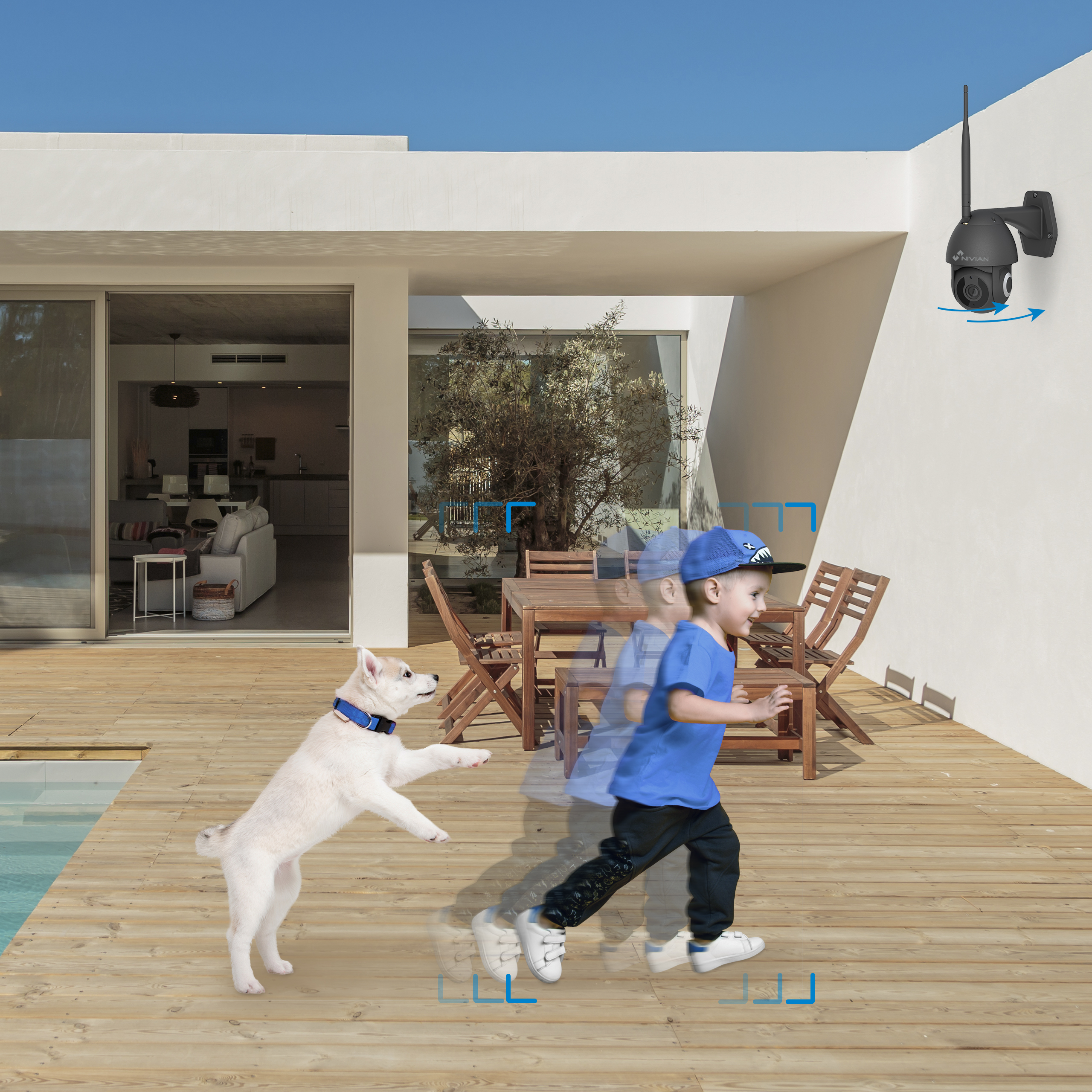 Un perro corre hacia un niño en una terraza, con una cámara de seguridad en la pared.