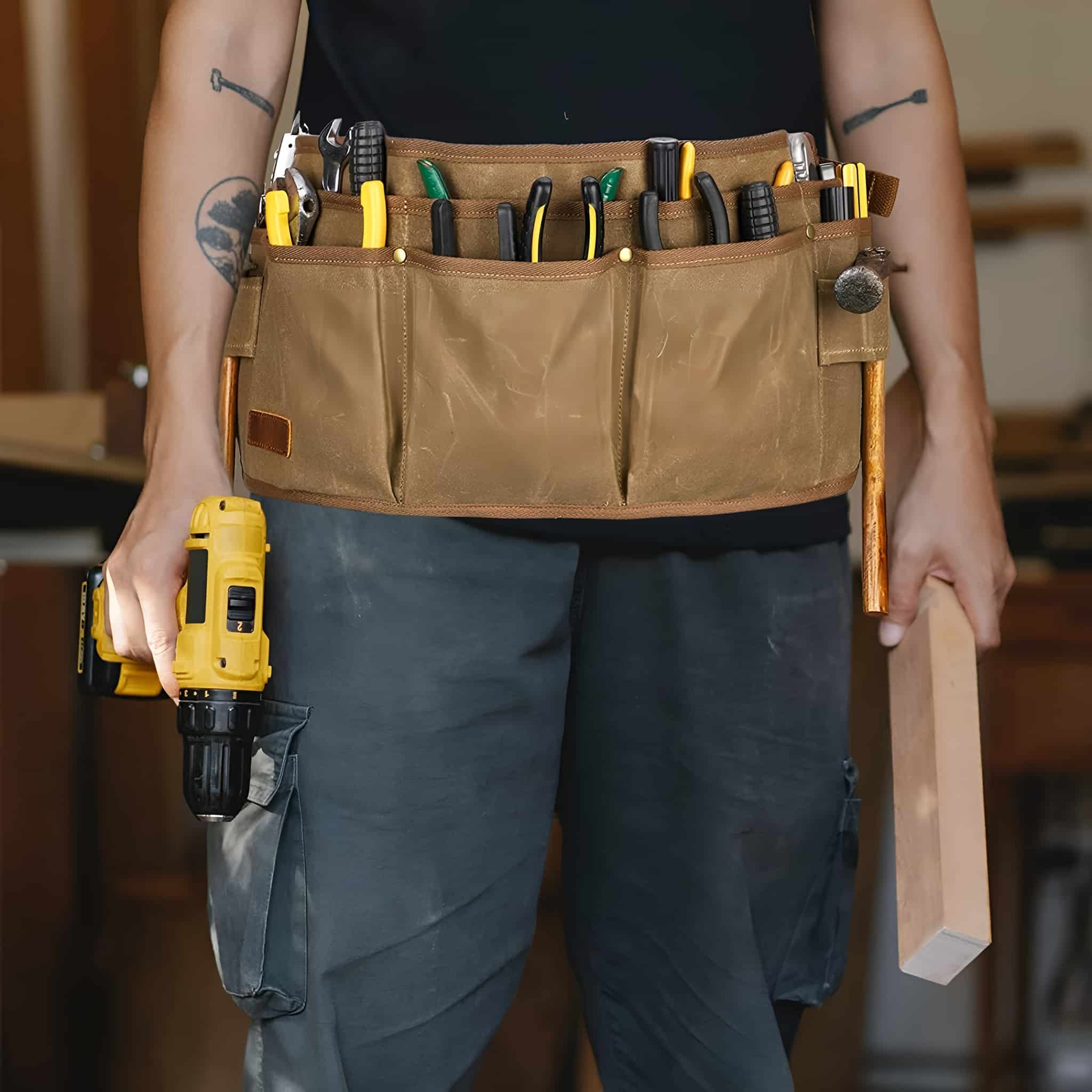 Ein Zimmermann mit Werkzeuggürtel, Bohrmaschine und Holz vor verschwommenem Hintergrund.