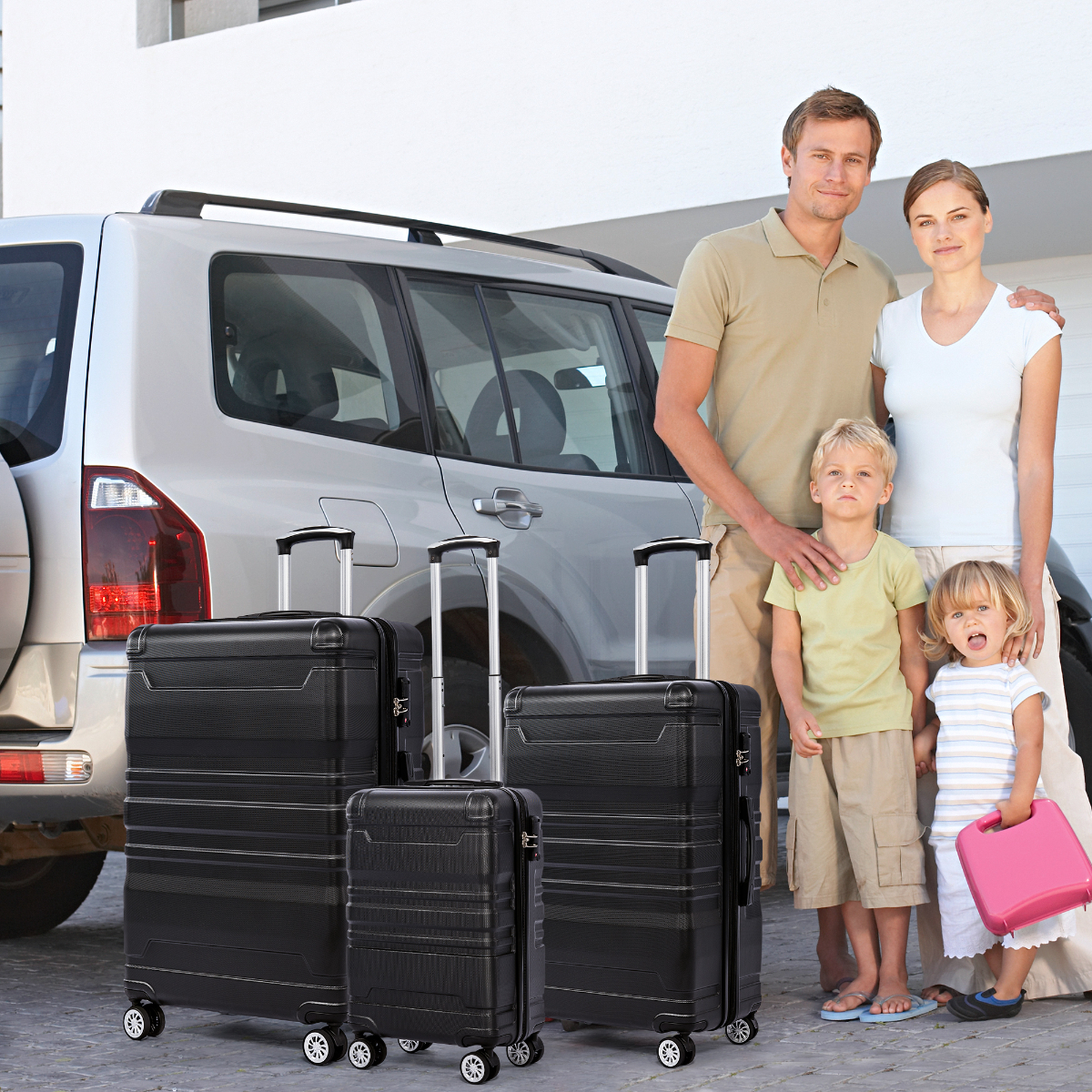 Eine Familie steht vor einem silbernen SUV mit schwarzen Koffern. Die Familie umfasst Eltern und zwei Kinder.