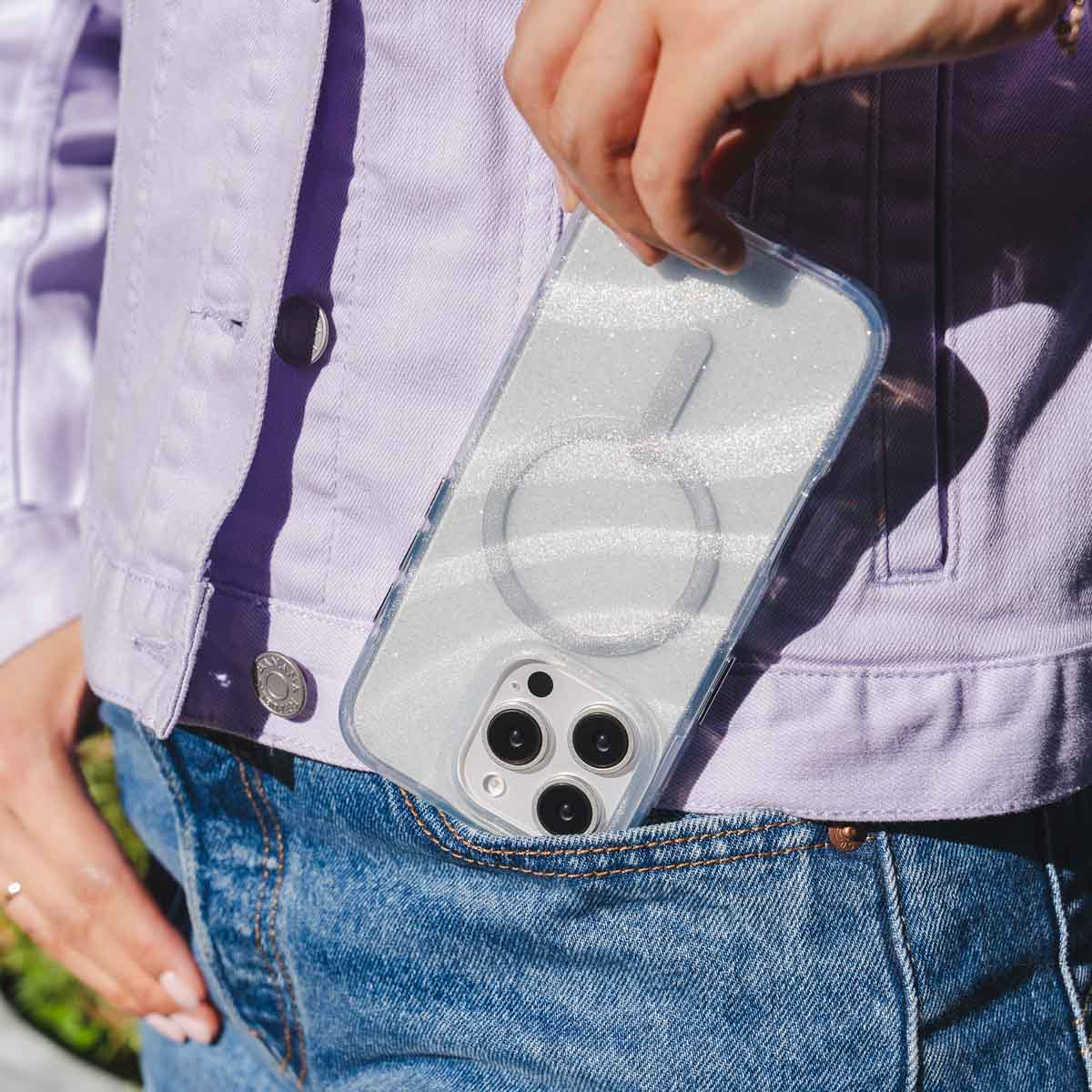 Vrouw die een telefoon in een glinsterende hoes vasthoudt. De telefoon zit in haar zak.