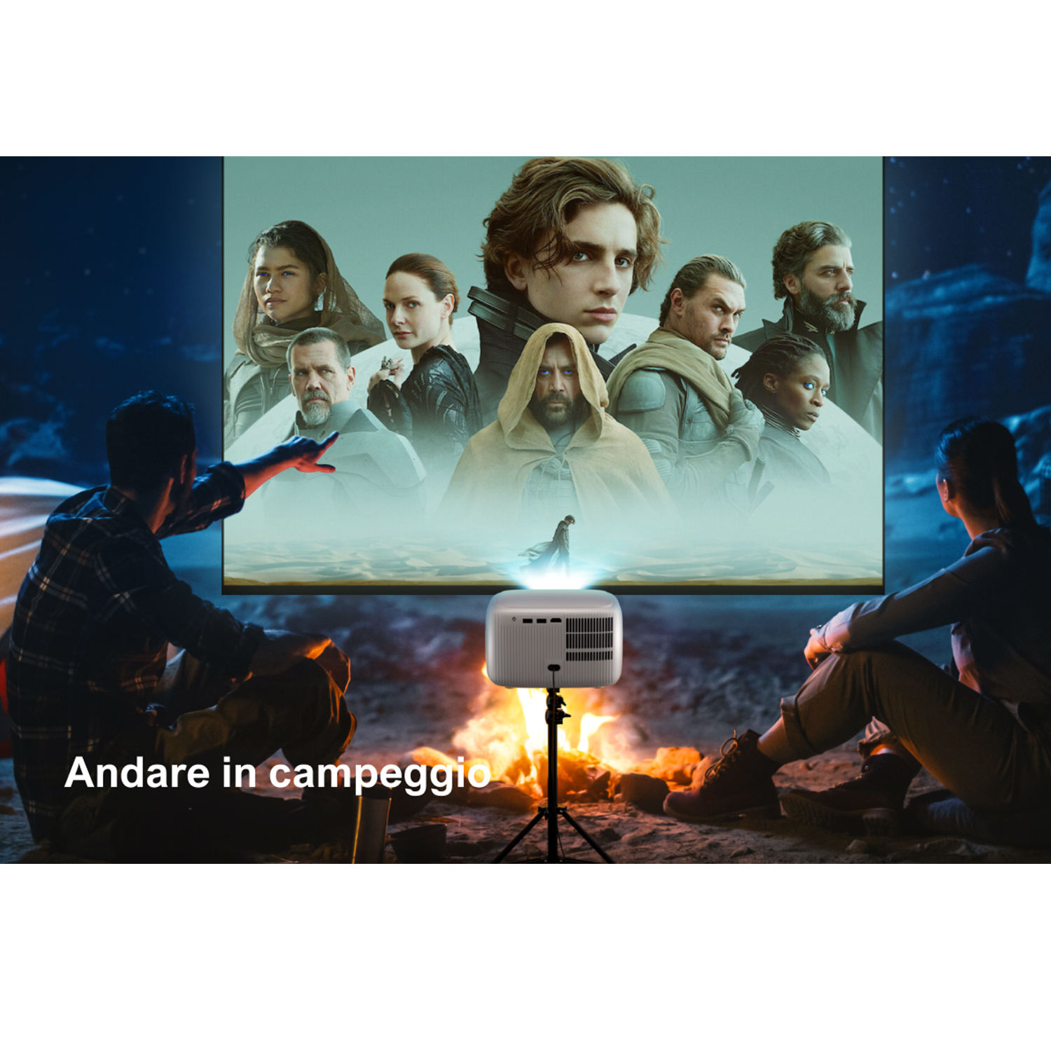 Persone che guardano un film proiettato su uno schermo durante il campeggio, con fuoco.
