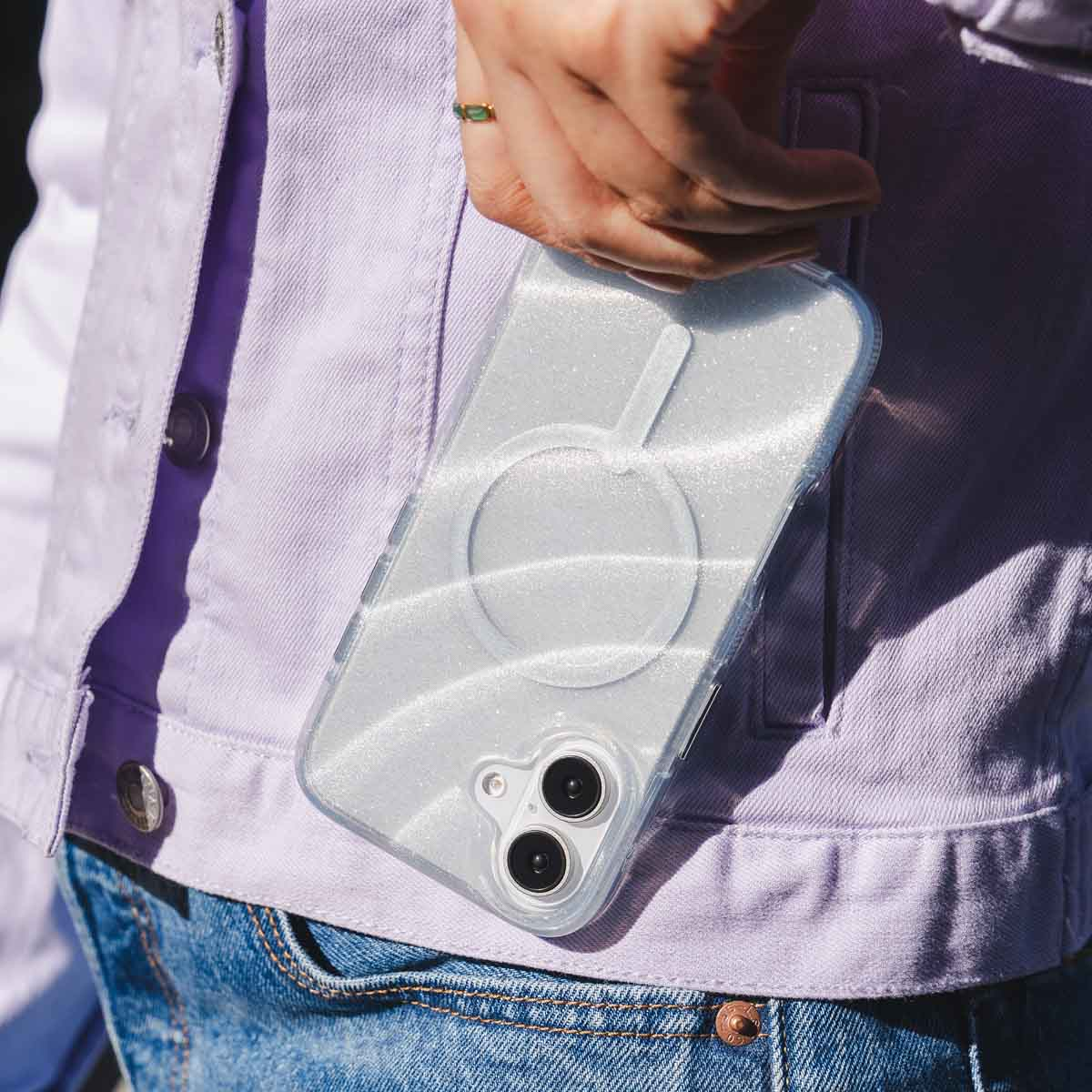 Person hält Telefon in der Tasche. Telefon hat transparente Hülle mit weißem Glitzer.