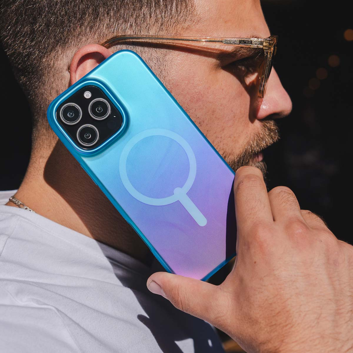 Uomo che tiene in mano un telefono con una custodia blu e viola. Il telefono è vicino all'orecchio.