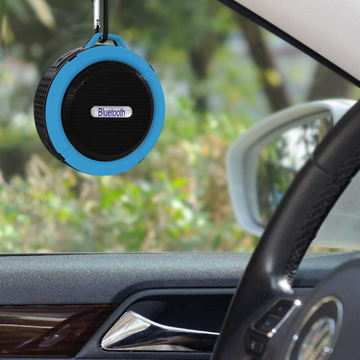 Ein blau-schwarzer Bluetooth-Lautsprecher hängt in einem Auto, der Innenraum ist sichtbar.