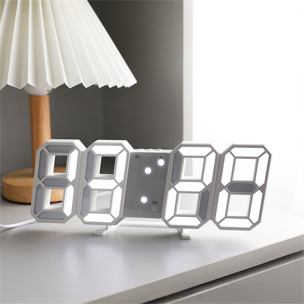 Eine Digitaluhr, die die Zeit anzeigt, auf einer weißen Oberfläche, mit einer Lampe im Hintergrund.