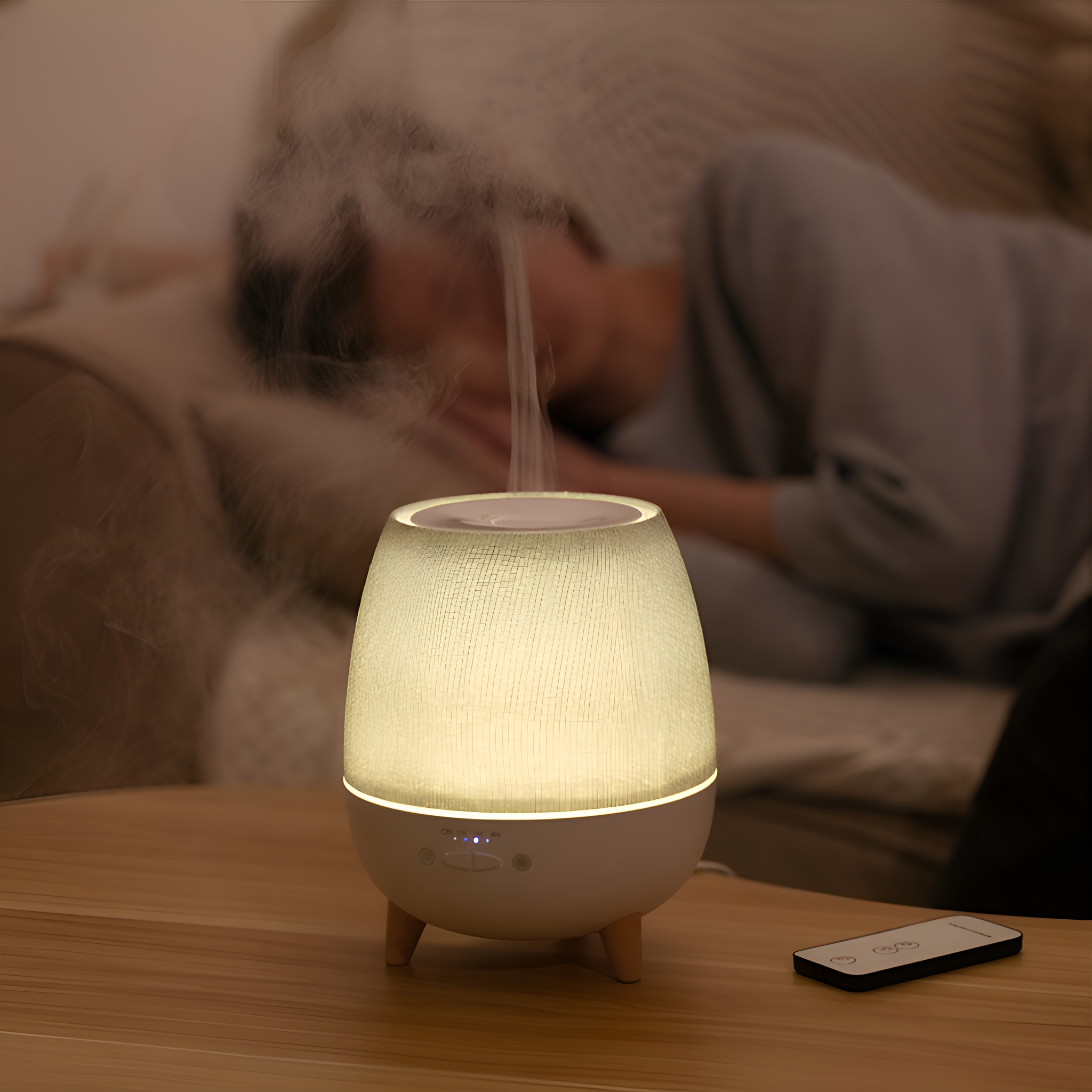 Aromatherapie-Diffusor auf einem Holztisch. Eine Person schläft im Hintergrund.