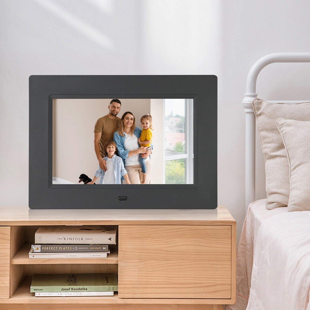 Digitaler Bilderrahmen mit Familienfoto auf einem Tisch.