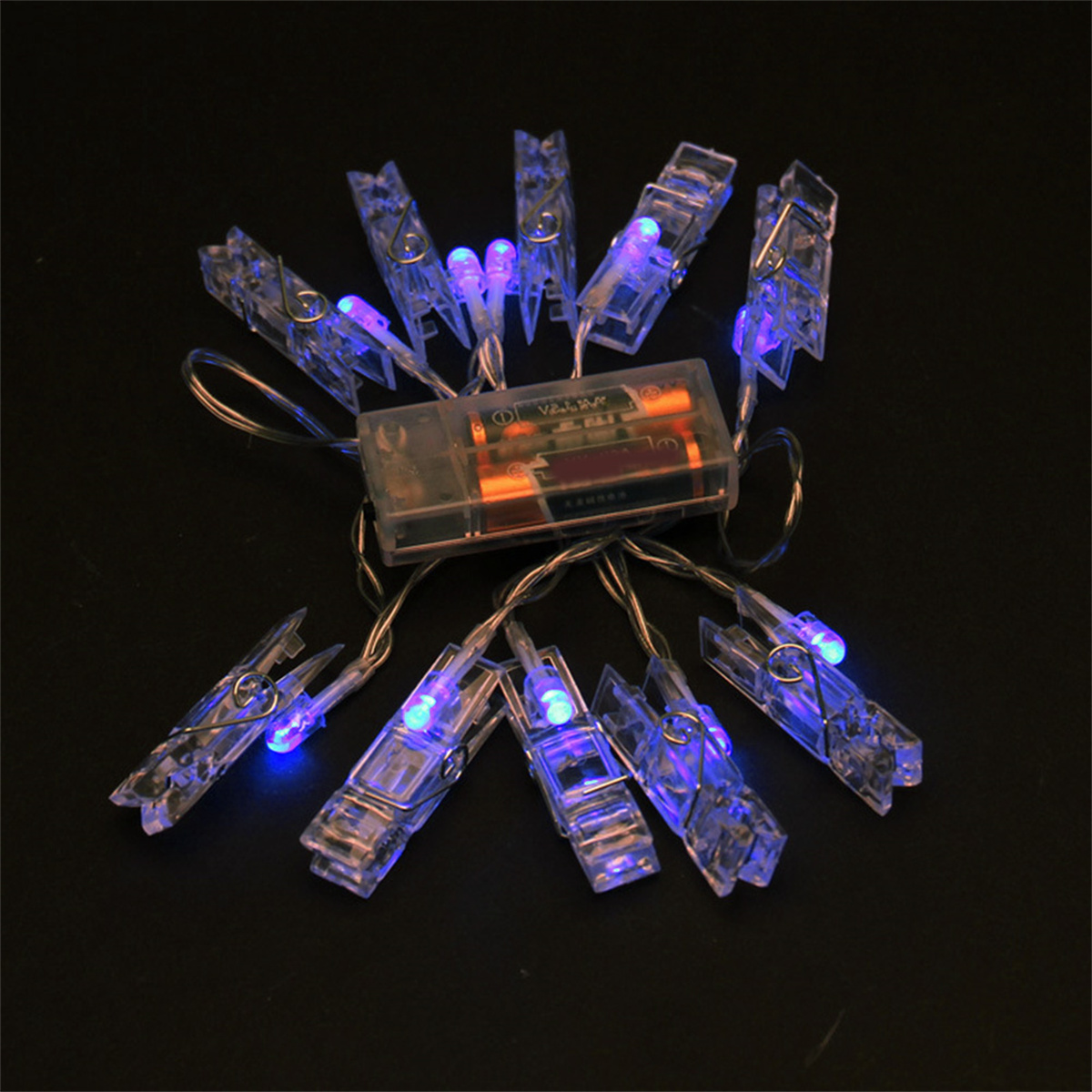 Lichterkette mit transparenten Clips und blauen Lichtern. Batteriepack und Drähte. Dunkler Hintergrund.