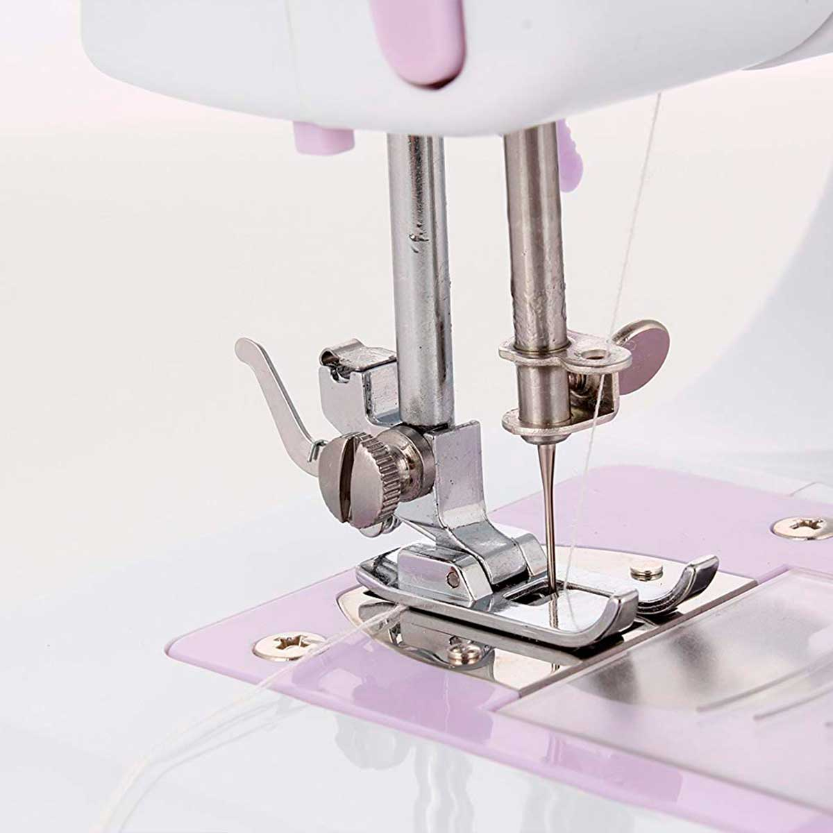 Zbliżenie igły maszyny do szycia, srebrnej i chromowanej, z nicią przechodzącą przez materiał.