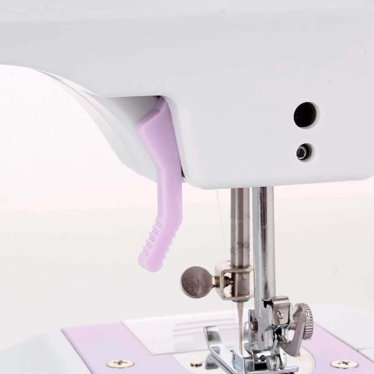 Szczegół maszyny do szycia: Fioletowa dźwignia, igła i stopka. Biały korpus maszyny. Białe tło.