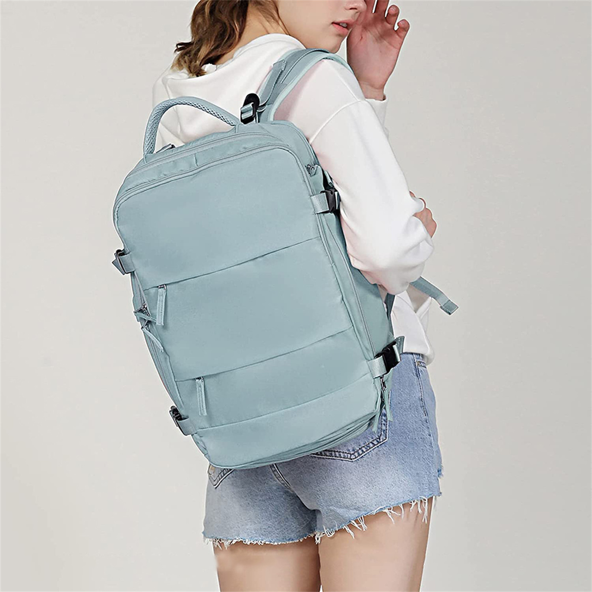 Blauer Rucksack, getragen von einer Frau. Rucksack hat mehrere Riemen und Taschen.