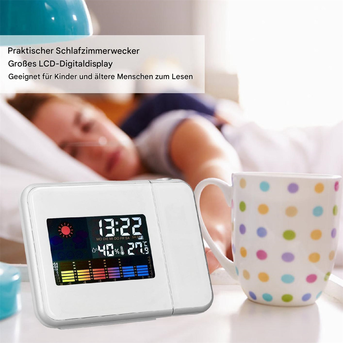 Weißer Wecker mit Zeitanzeige, Tasse mit Punkten und schlafende Person im Hintergrund.