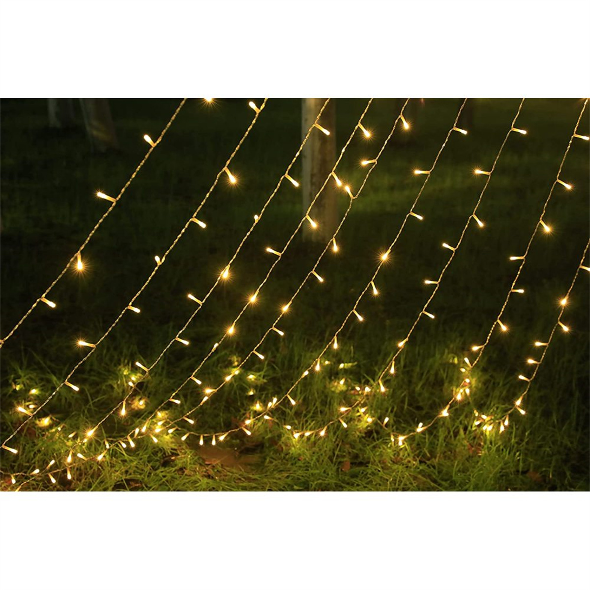 Lichterketten hängen im Freien, warmgelbe Lichter auf grünem Gras.