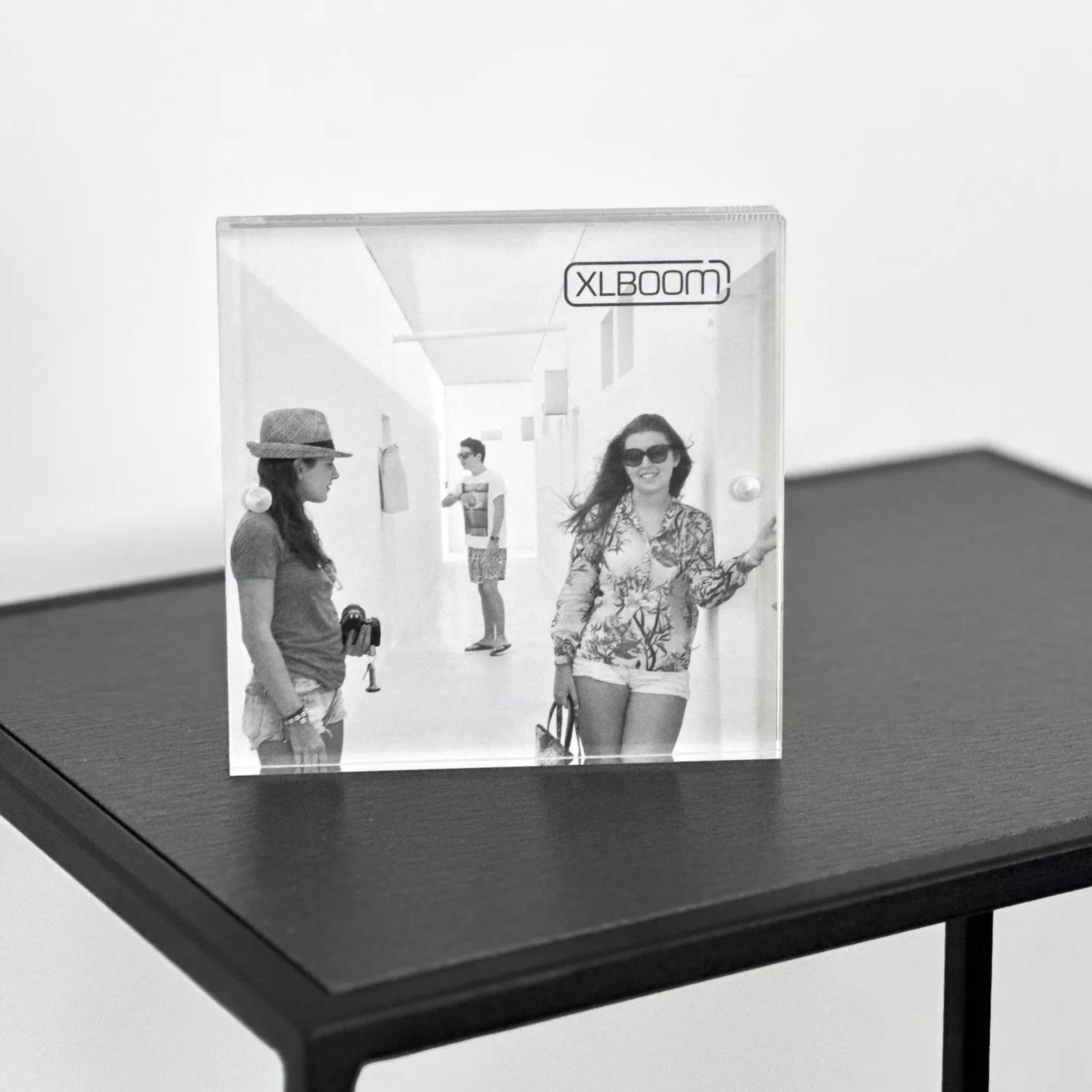 Czarno-biała ramka na zdjęcia na czarnym stole, z dwiema kobietami i mężczyzną na zdjęciu.