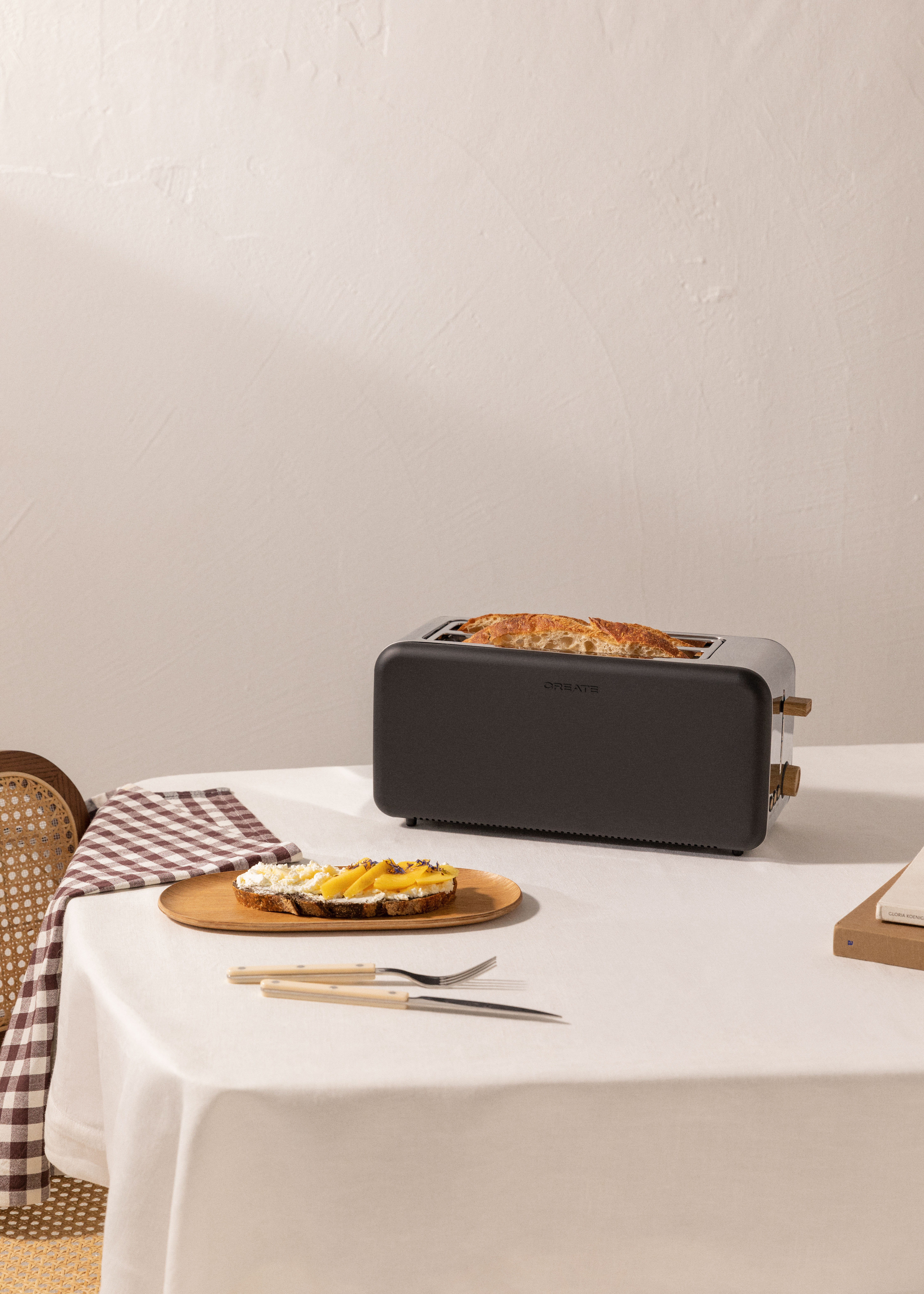 Table avec toasts, grille-pain, planche en bois et ustensiles. Nappe blanche.